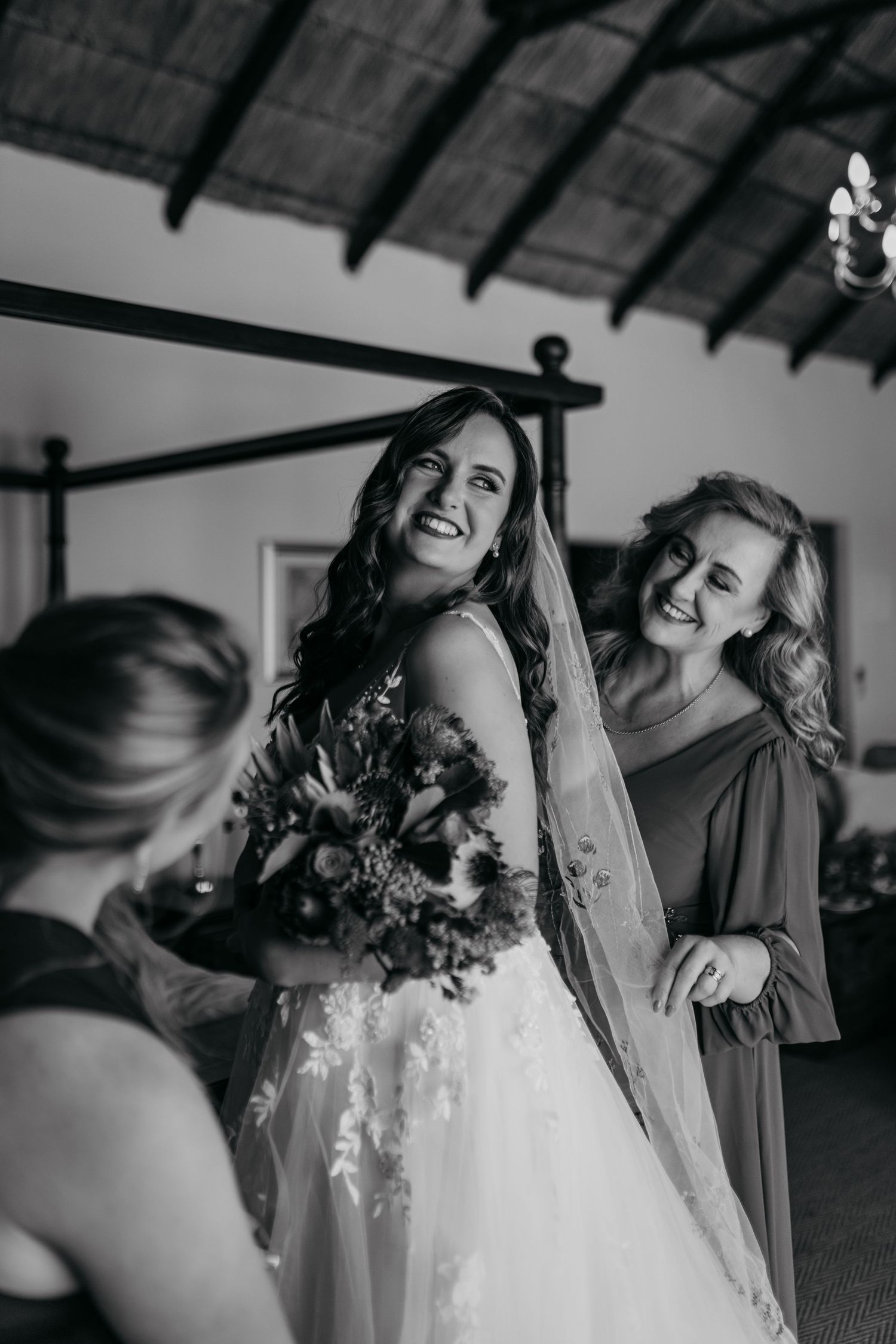 A joyful wedding preparation moment captured in black and white as the bride gets ready with her bridal party.