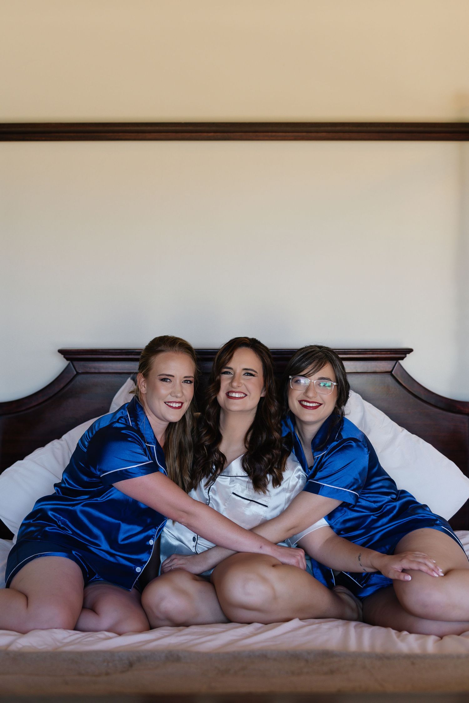 Three people in matching blue and white sleepwear lounge together on a bed sharing a candid moment.