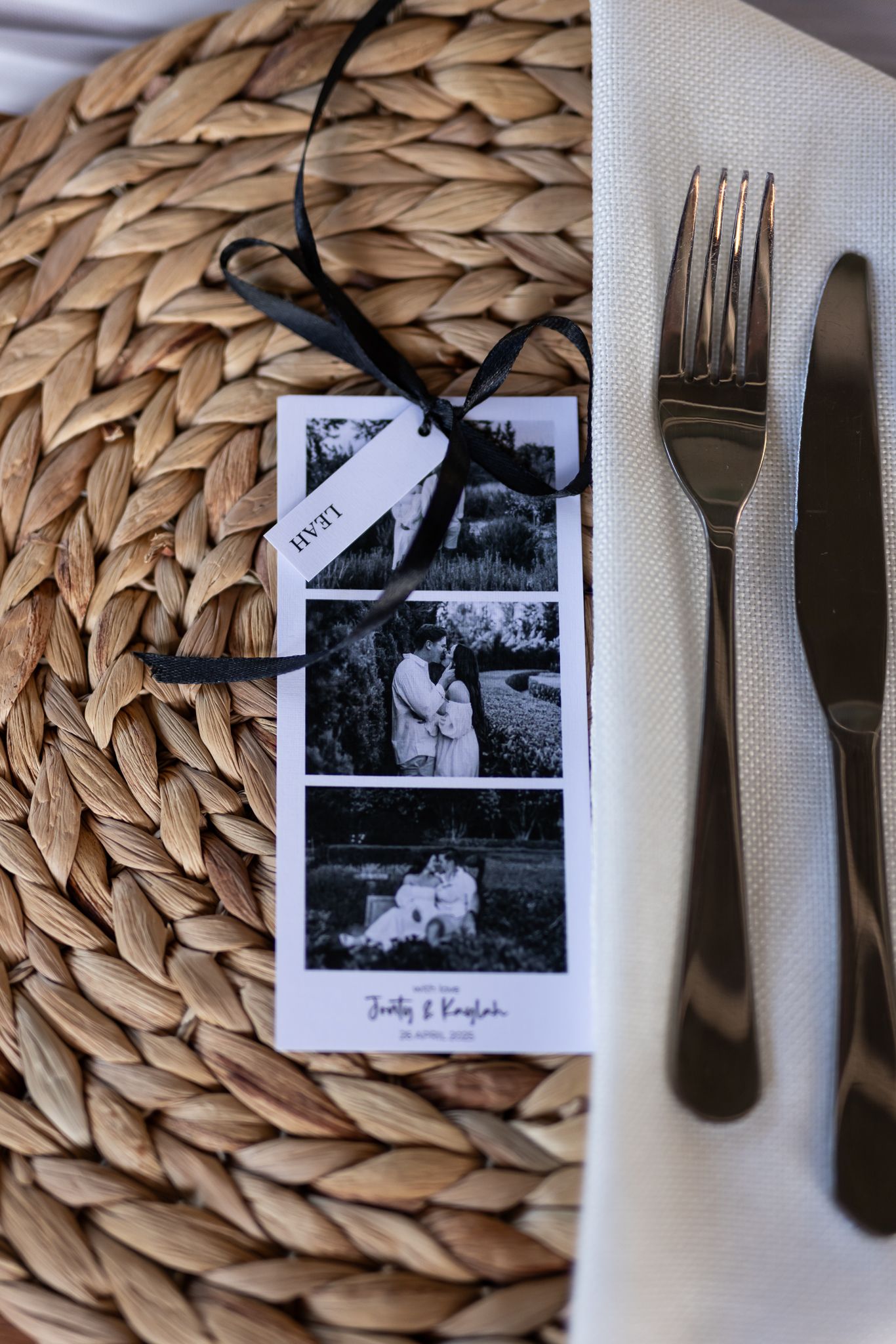 A place setting with vintage photo strips on a woven placemat next to silverware.