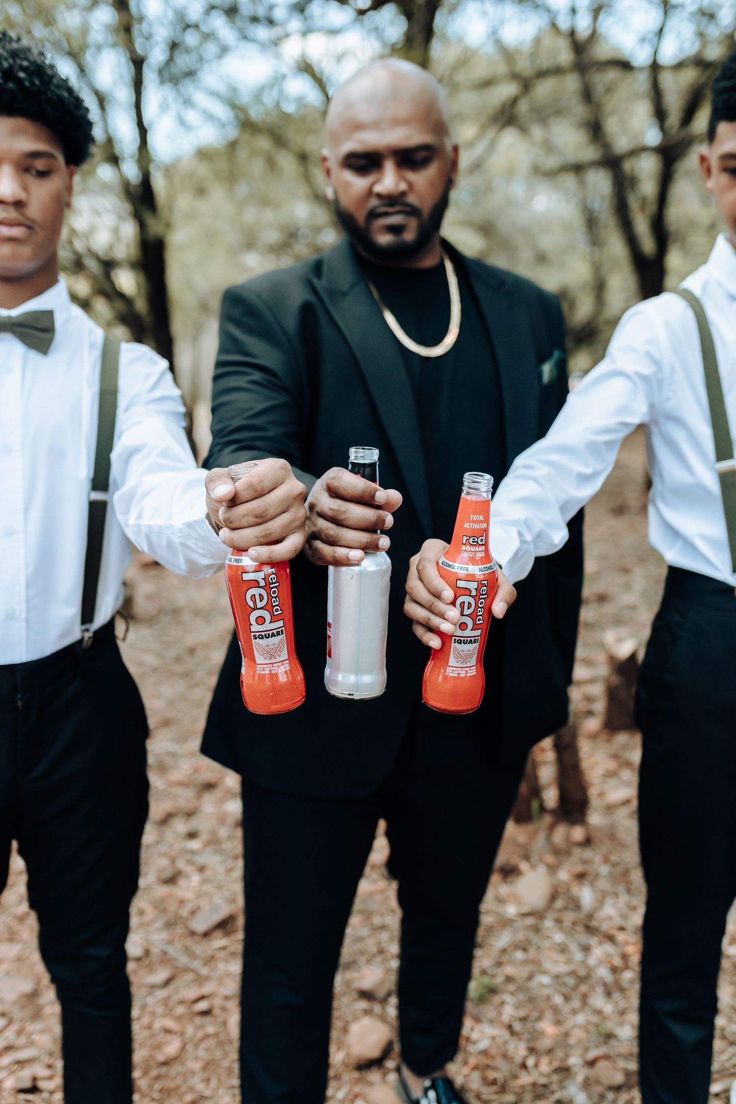 Group in formal wear holding beverages together outdoors.