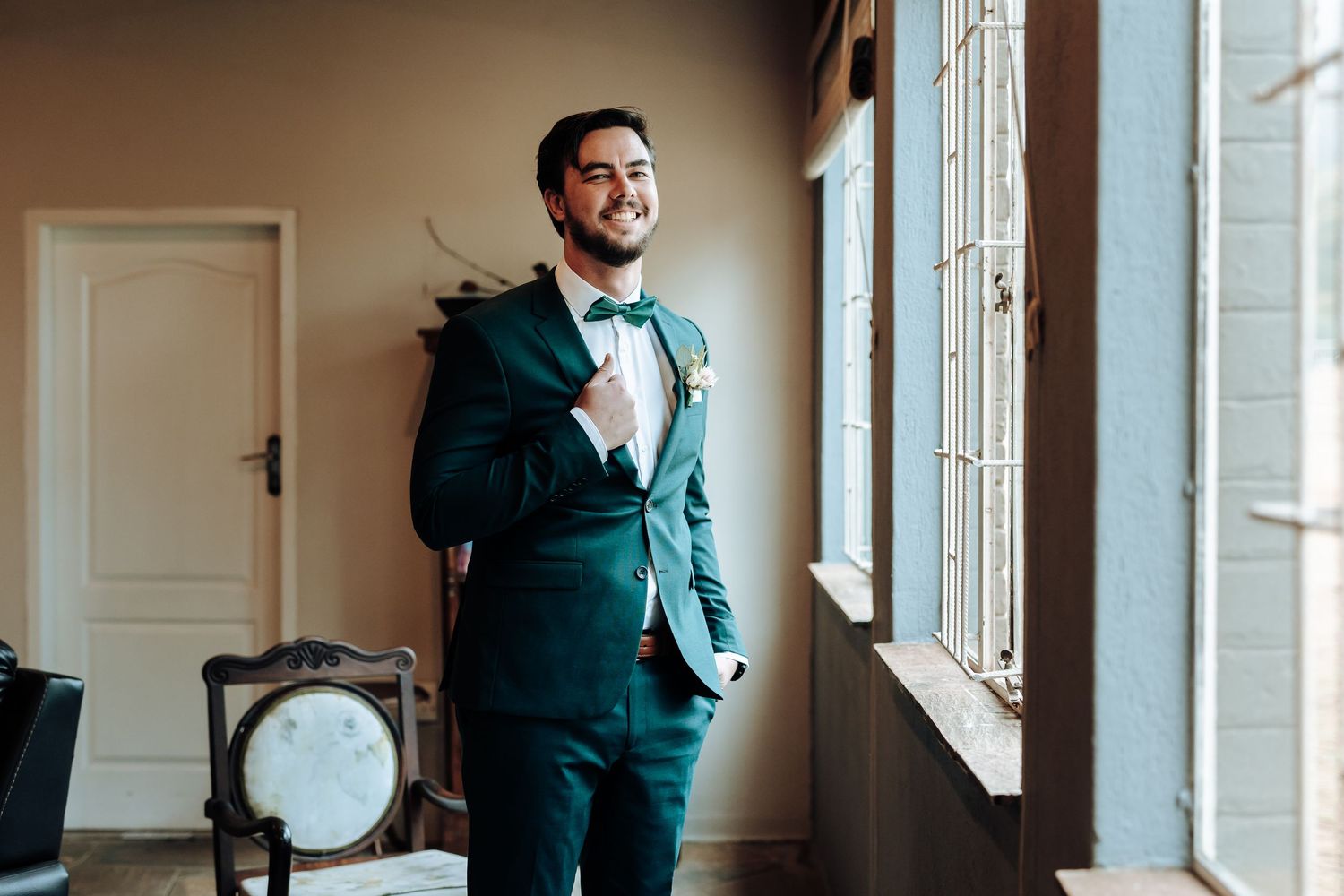 Emerald tuxedo showcased in natural window light with vintage furniture details.