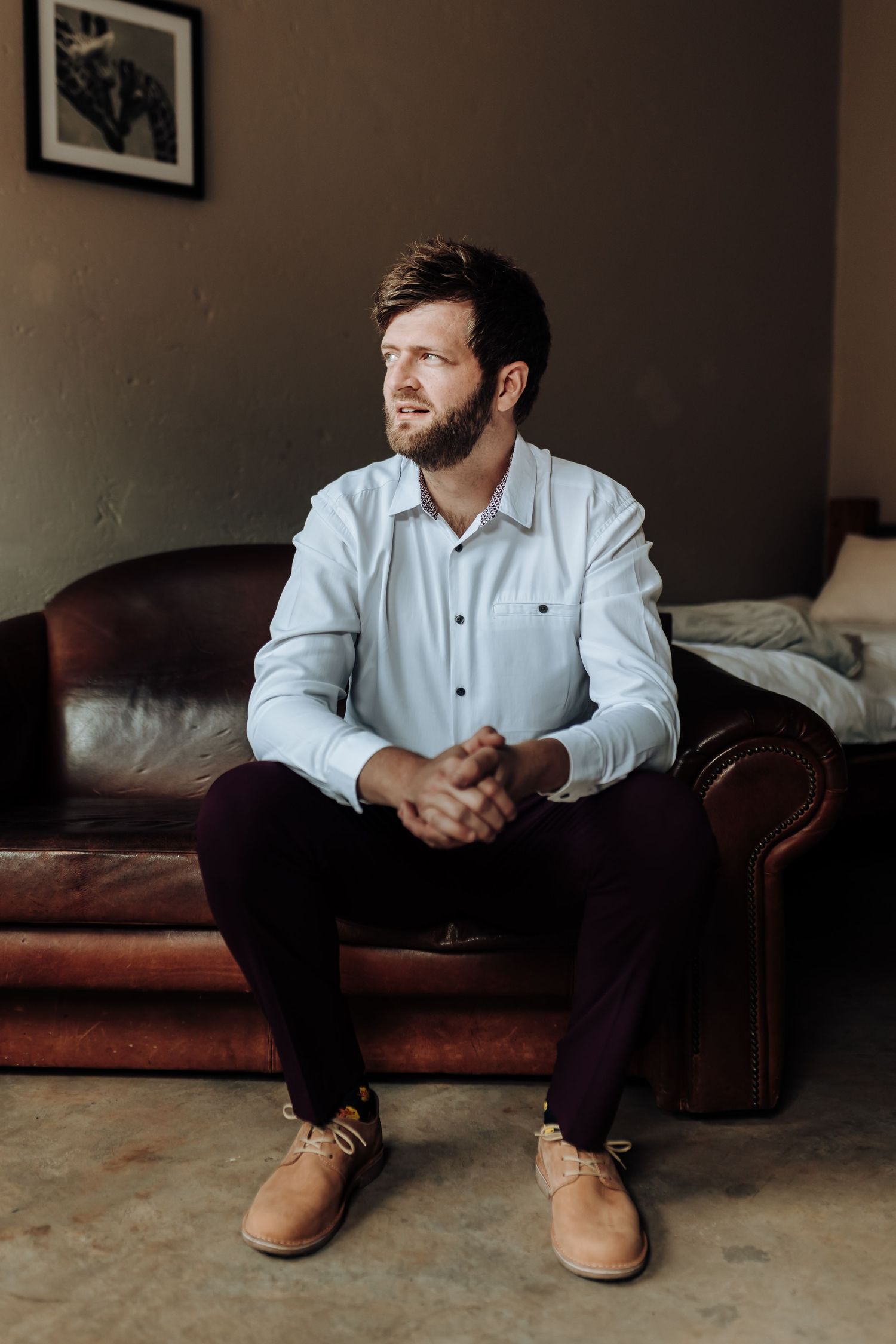 Side view of person seated on leather couch wearing white shirt and dark pants.