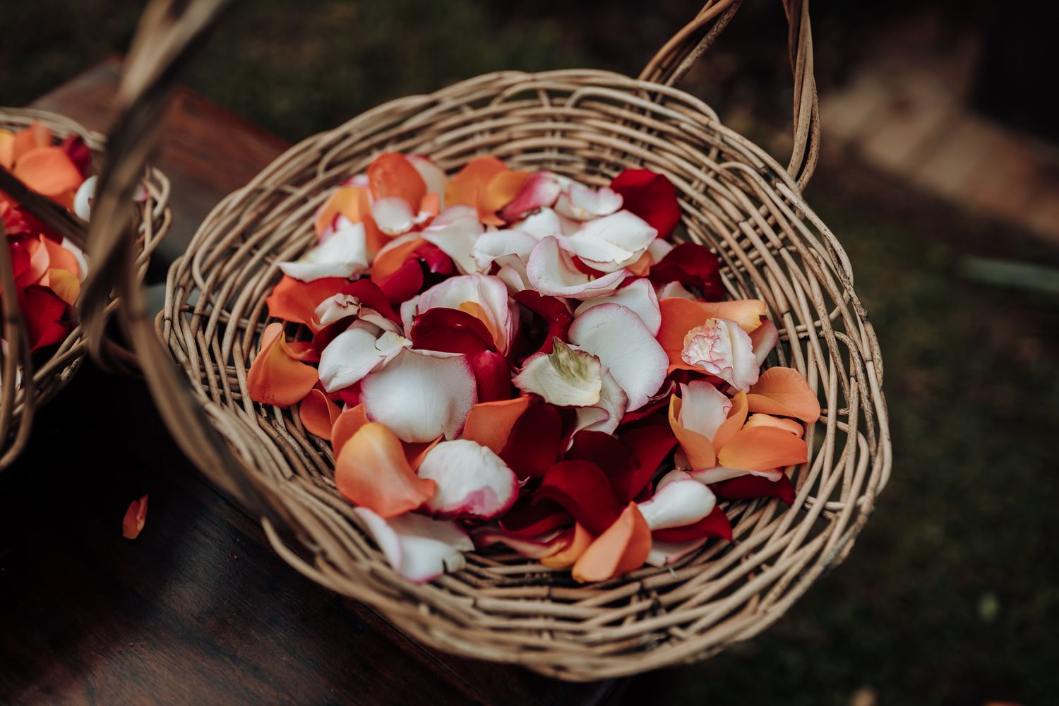 A woven basket filled with pink and white rose petals for a wedding ceremony.