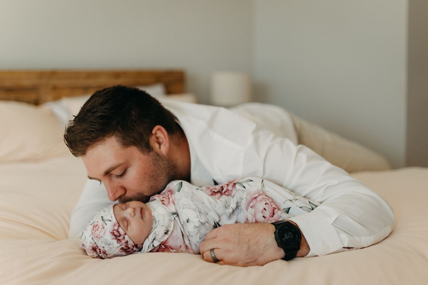 Someone sleeping peacefully under white bedding and floral pillowcases in natural morning light.
