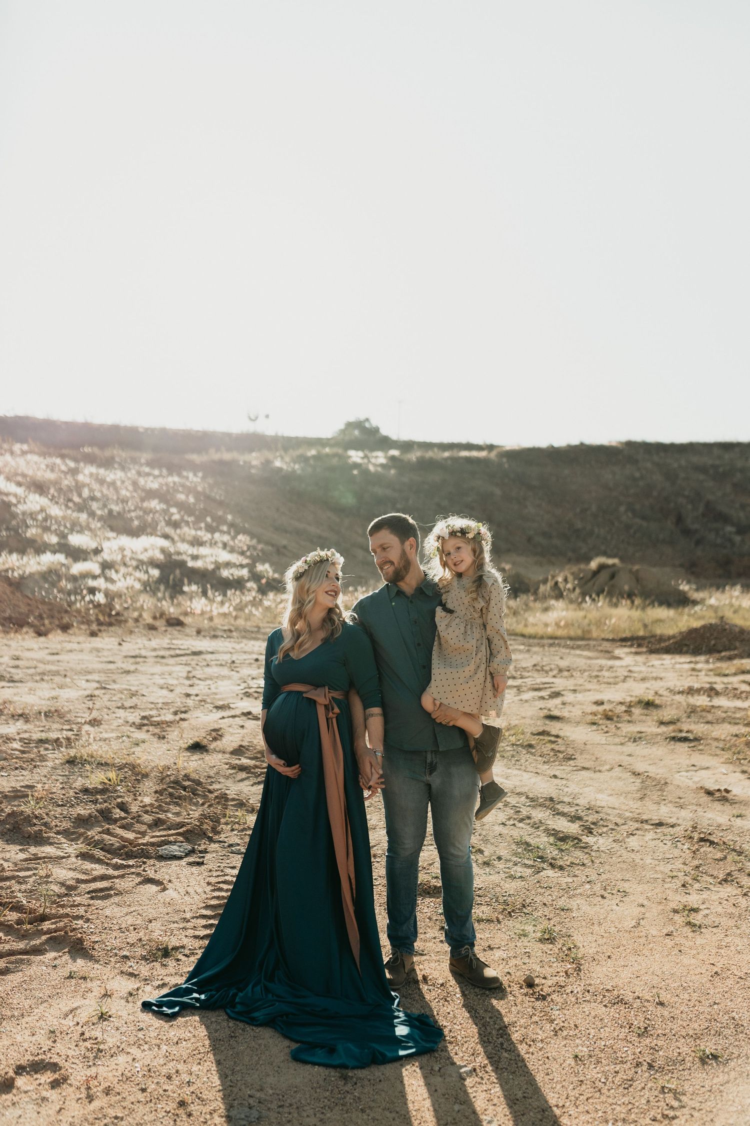 Three figures cast long shadows while standing together in a desert landscape during golden hour.