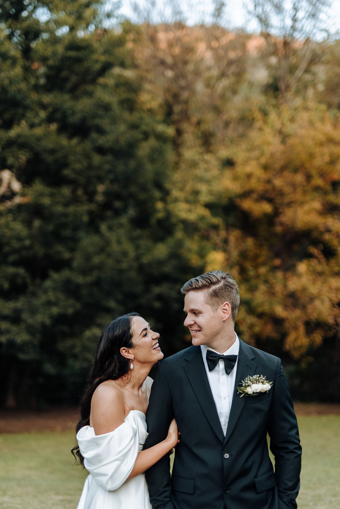 Candid wedding portrait of couple laughing together in outdoor setting.