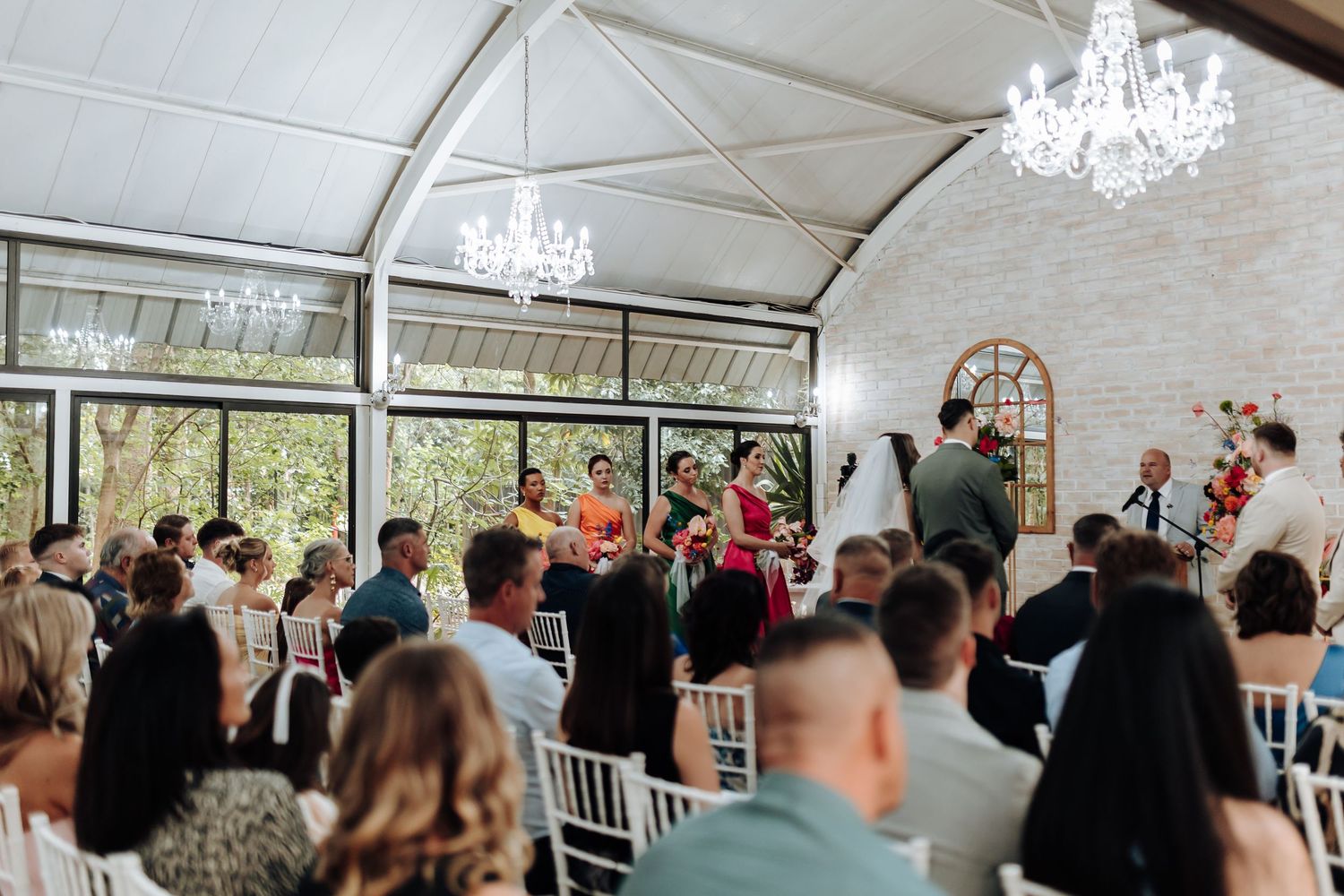 Elegant wedding reception venue with white chandeliers and guests mingling under a white tent structure.