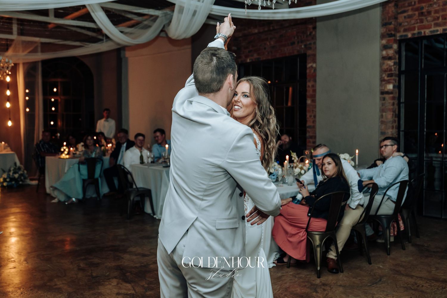Wedding reception venue decorated with string lights and white fabric draping across the ceiling.