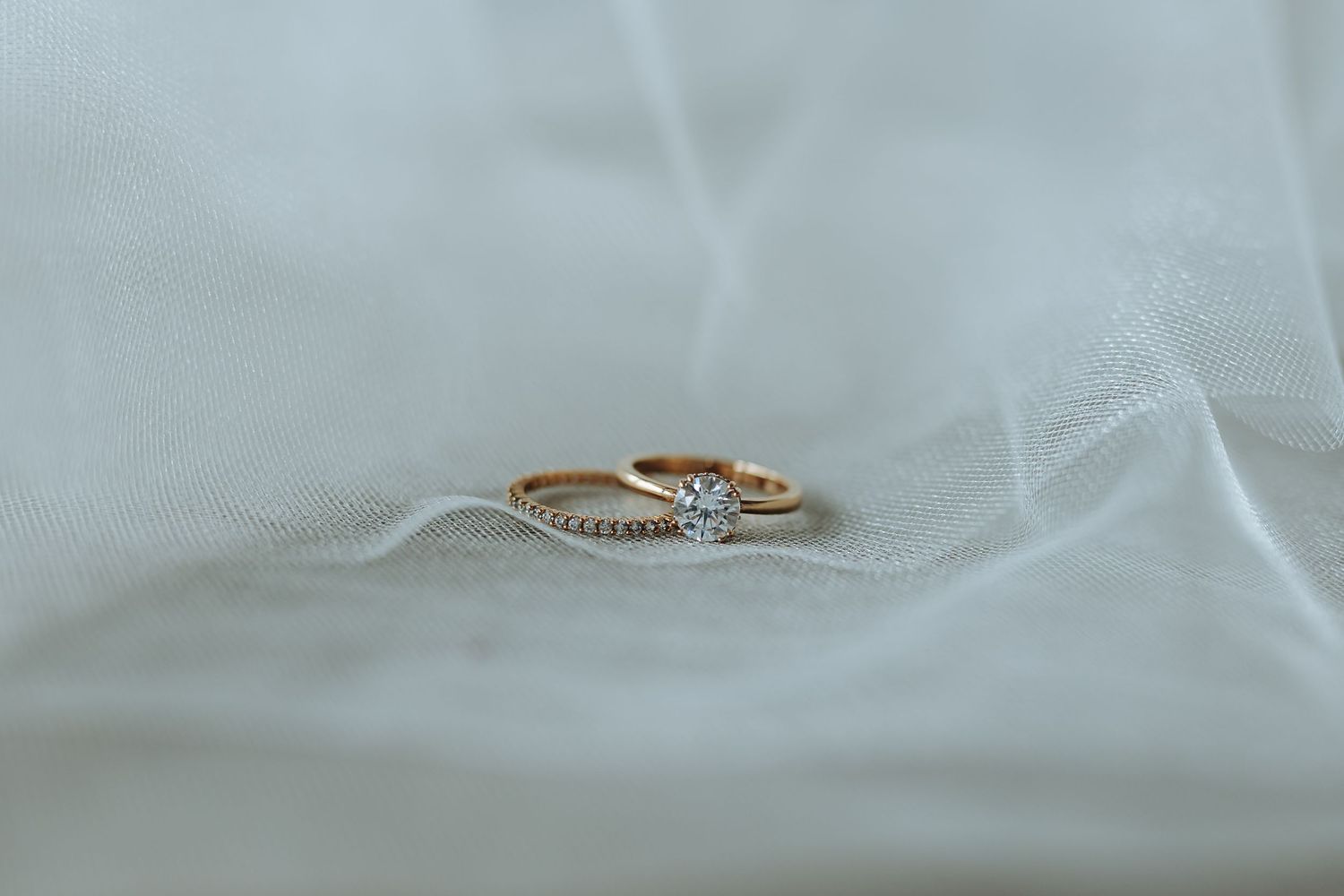 A delicate rose gold snake ring with coiled design and textured details on white fabric background.