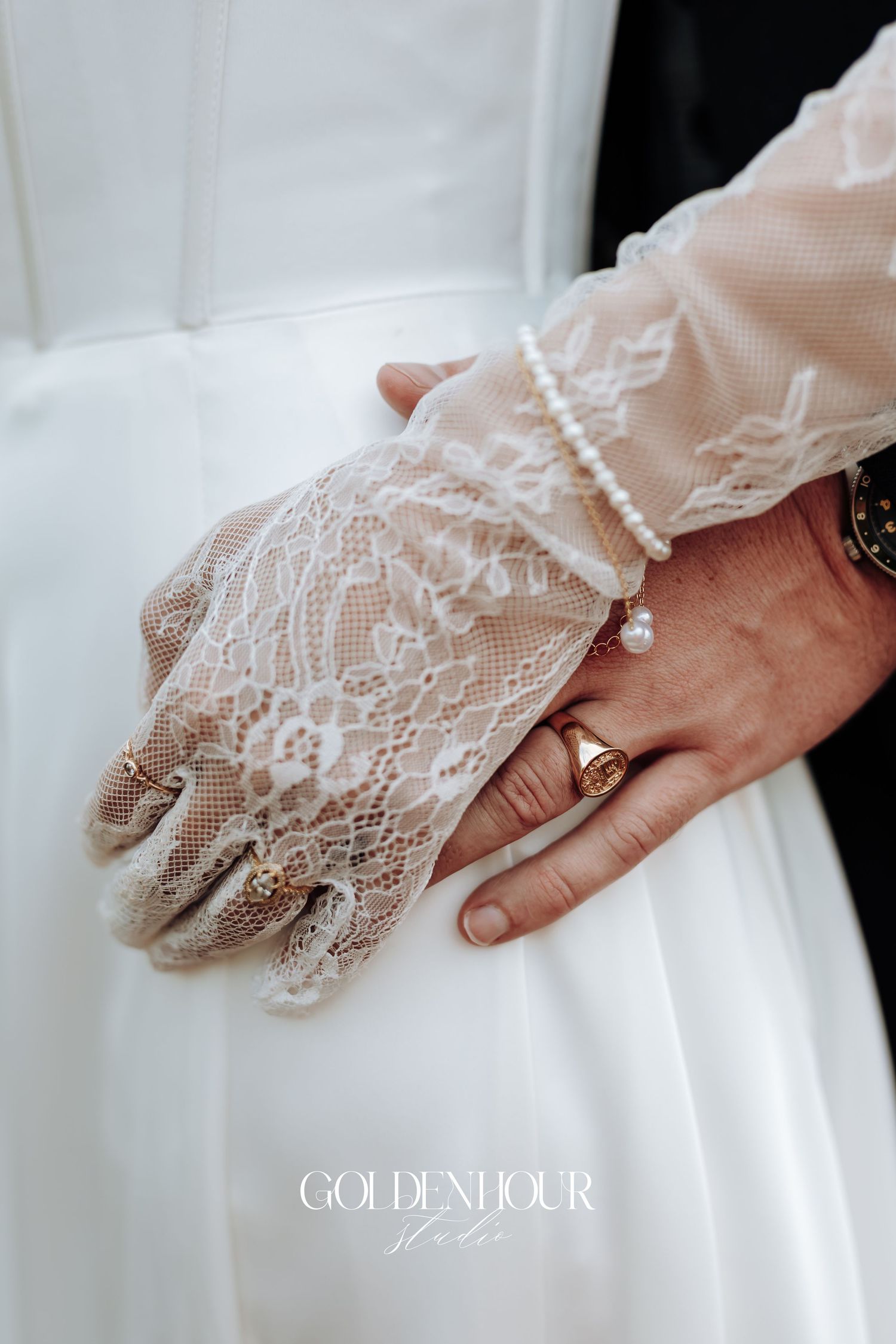 Close-up of delicate lace gloves touching white wedding dress fabric.
