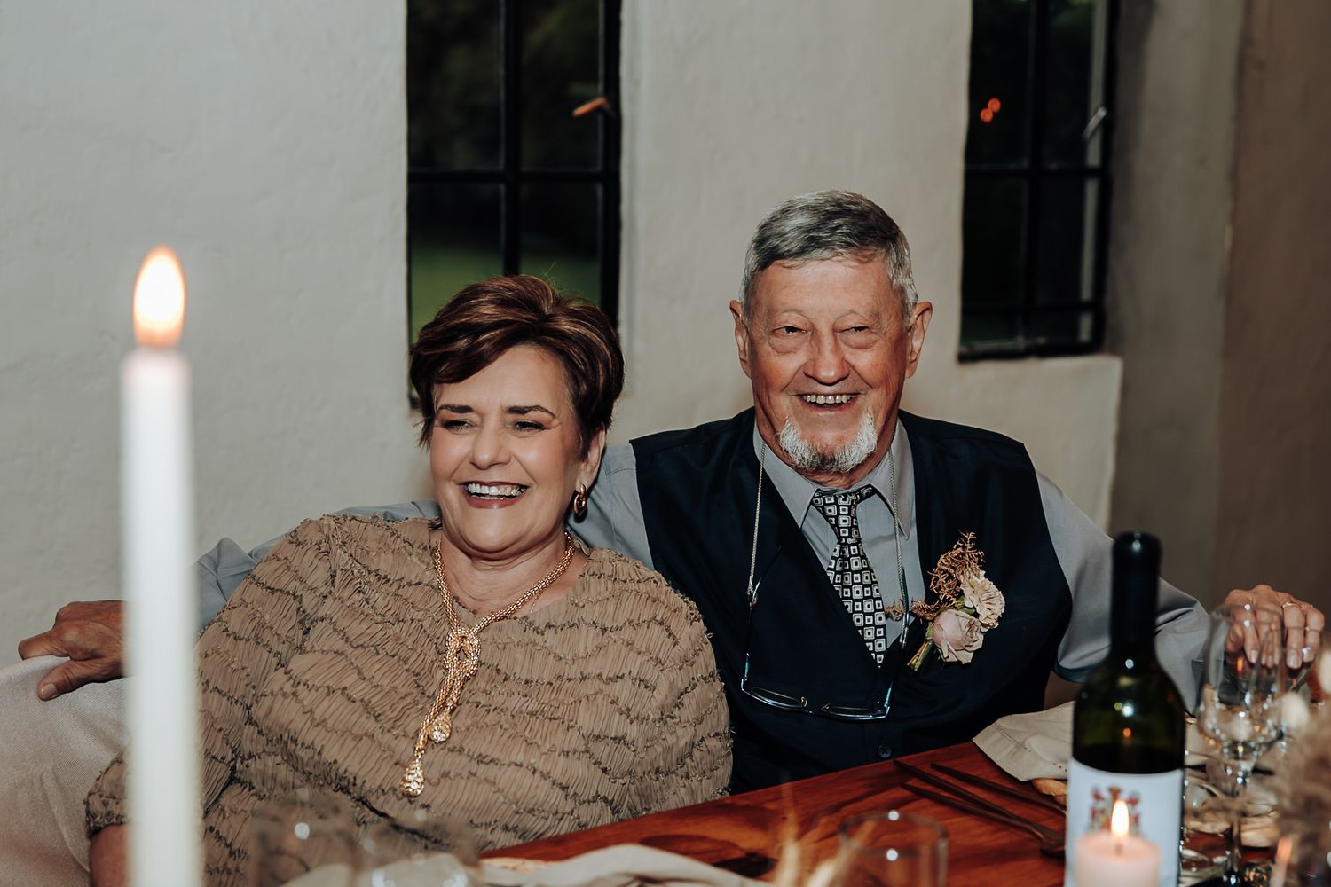 A group of people enjoying a meal together at a dining table with warm lighting in the background.