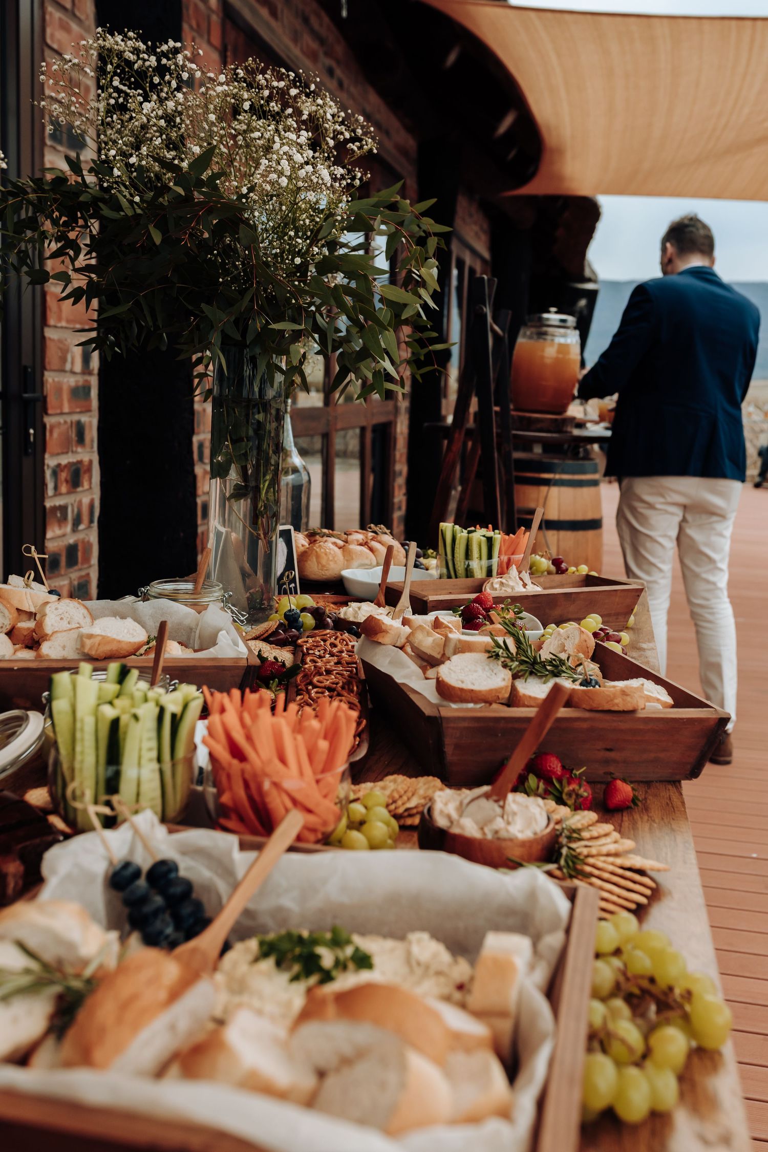 A close-up view of an elegant catering display with fresh vegetables, grapes, and appetizers arranged on a wooden surface.