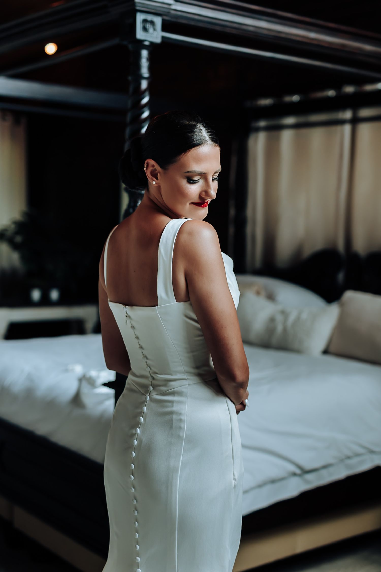 A series of photos showing the back details of an elegant white wedding dress with button closures in a dimly lit room.