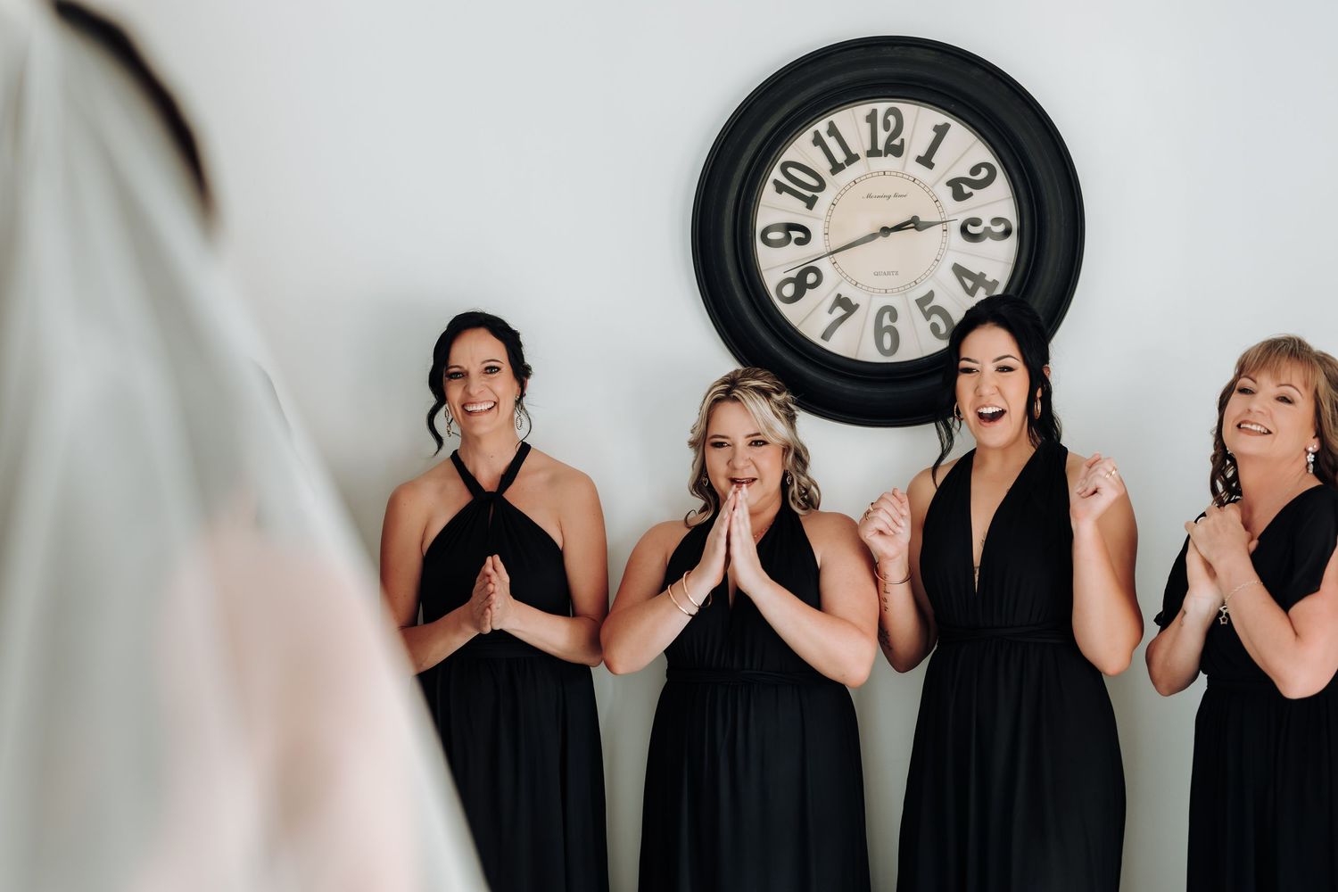 People in matching black attire stand in a row against a white background with a clock visible.