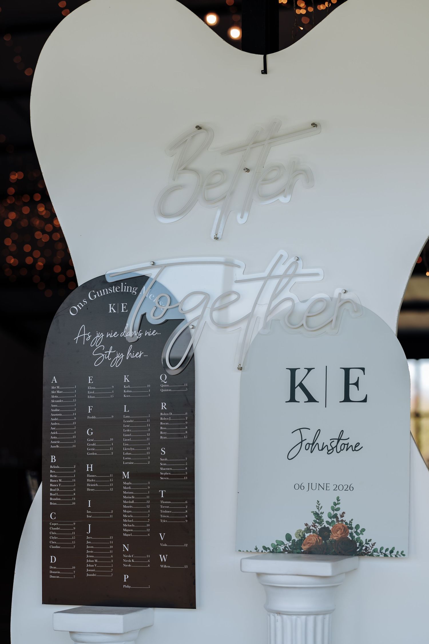 Wedding seating chart display with neon Better Together sign, KE Johnstone monogram, and floral accents dated 06 June 2026.