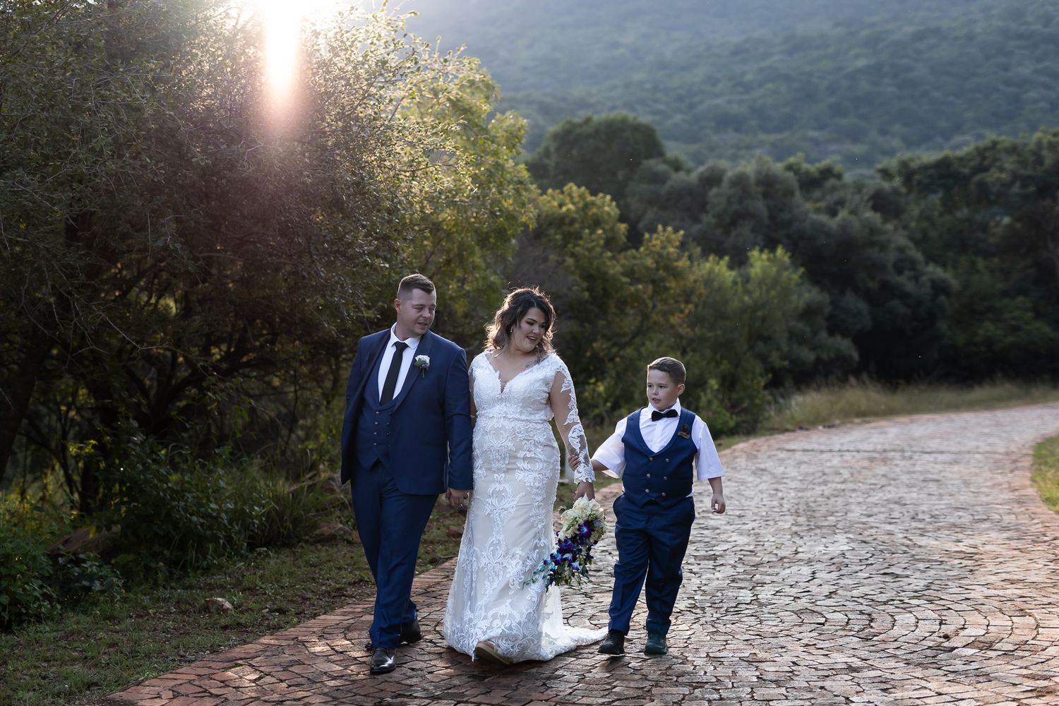 Wedding party walking along a scenic mountain path at sunset.