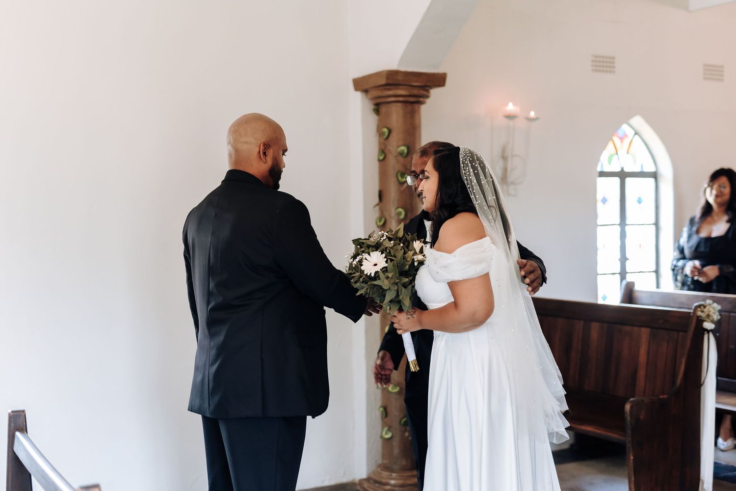A couple sharing a moment during their wedding ceremony in an elegant white chapel.