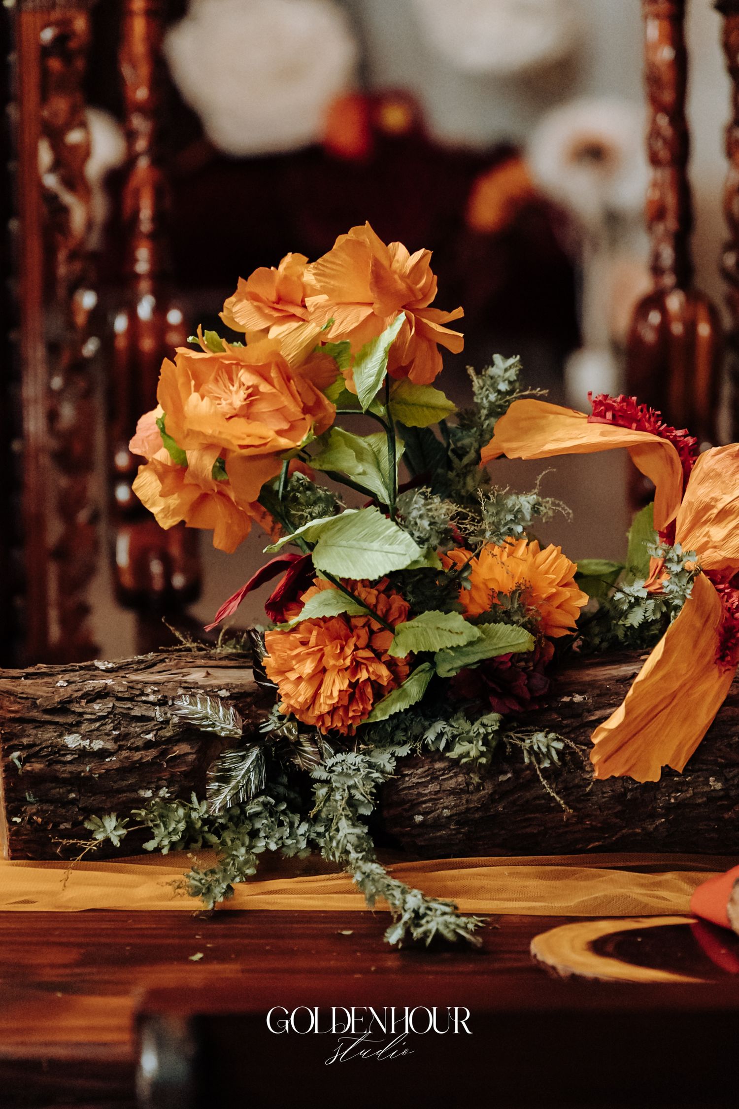 Elegant autumn wedding floral arrangement featuring orange roses and marigolds on rustic wood.