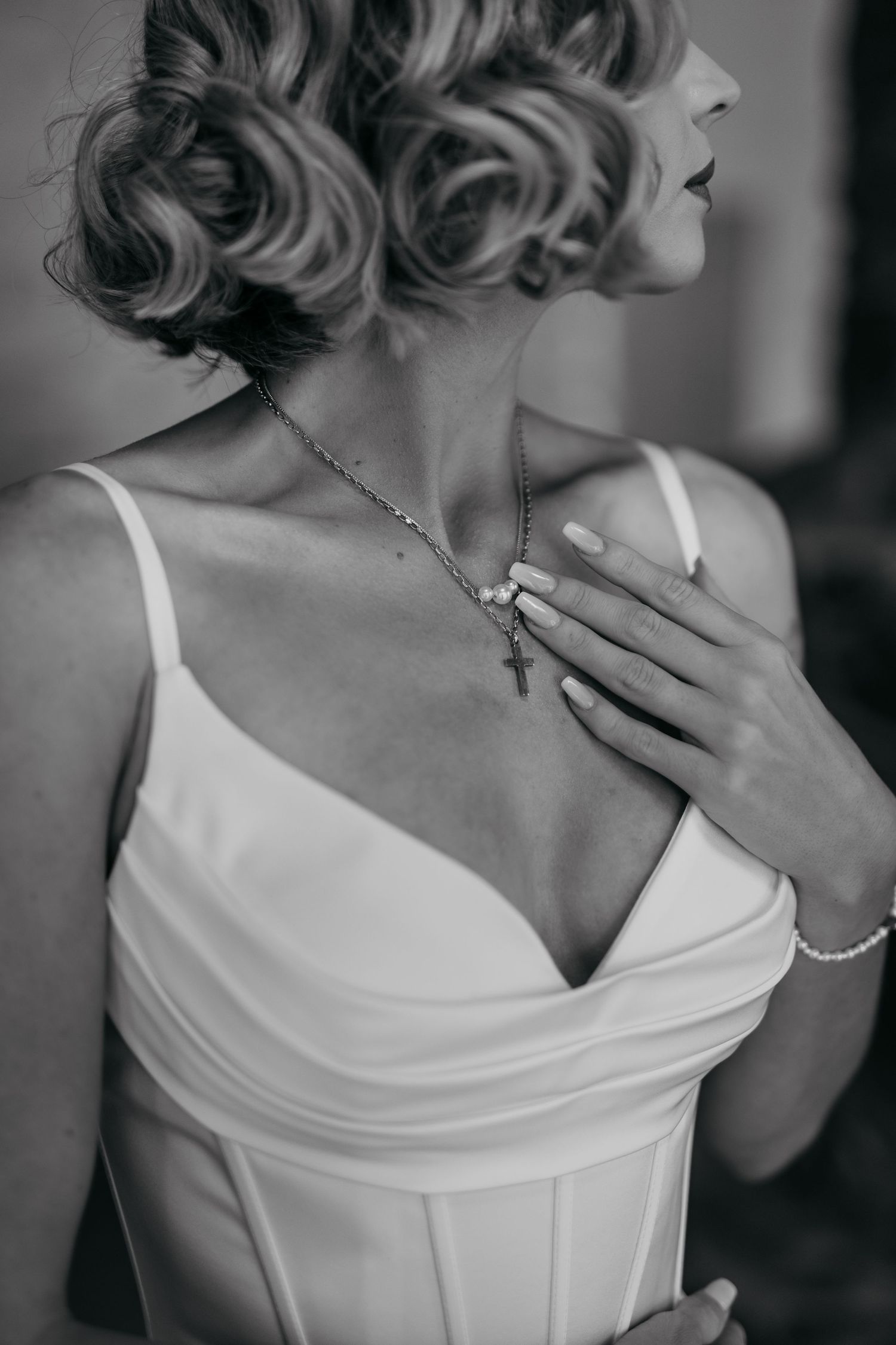 A series of black and white close-up shots showing details of an elegant white bridal gown with draped neckline.