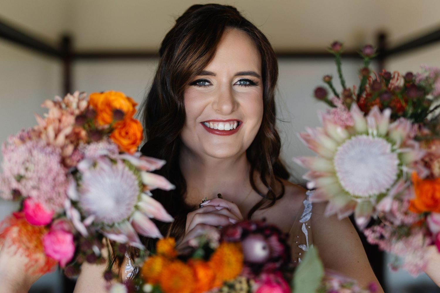 Wedding party celebrates with vibrant floral arrangements featuring pink and orange blooms against a light background.