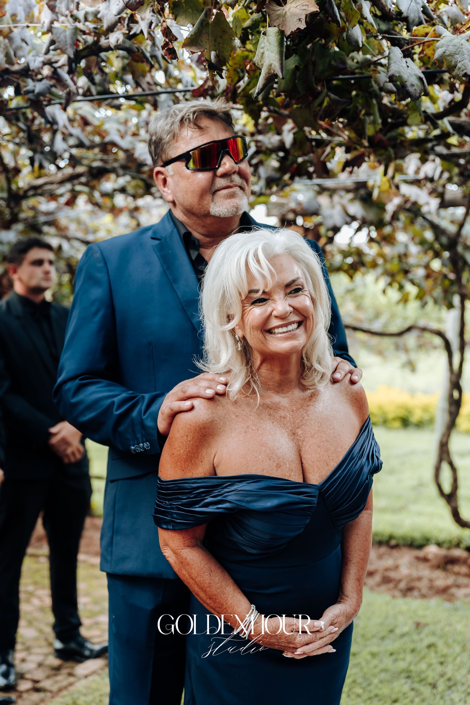 Candid moments of a couple laughing and embracing outdoors during a celebration in navy blue attire.