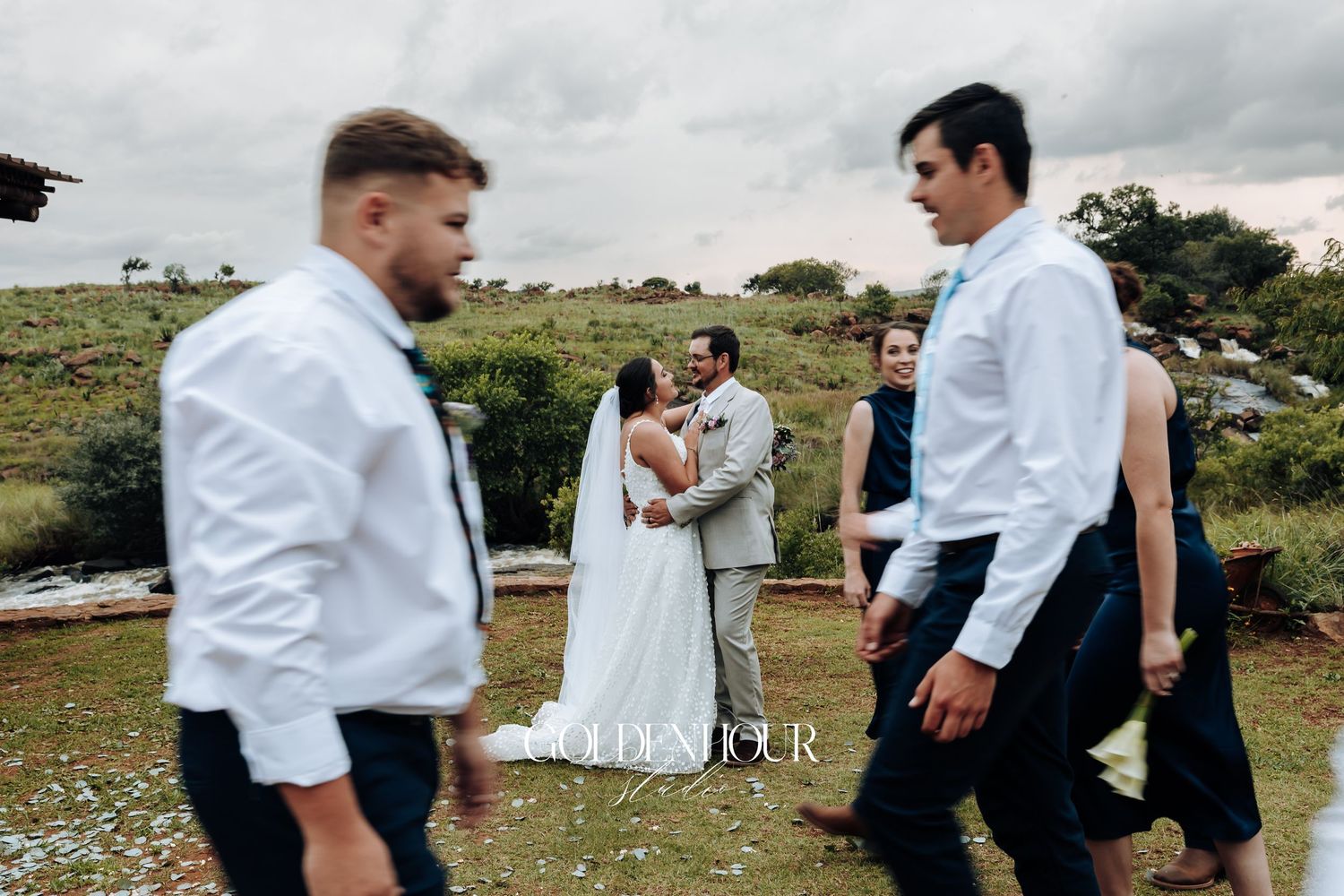 Wedding party members walk and pose along a scenic outdoor path.