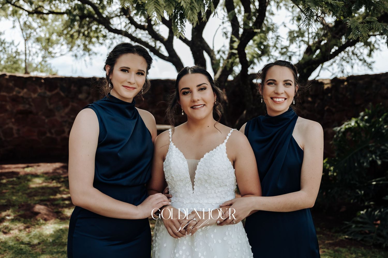 Wedding party poses together outdoors with bridesmaids in navy blue dresses.