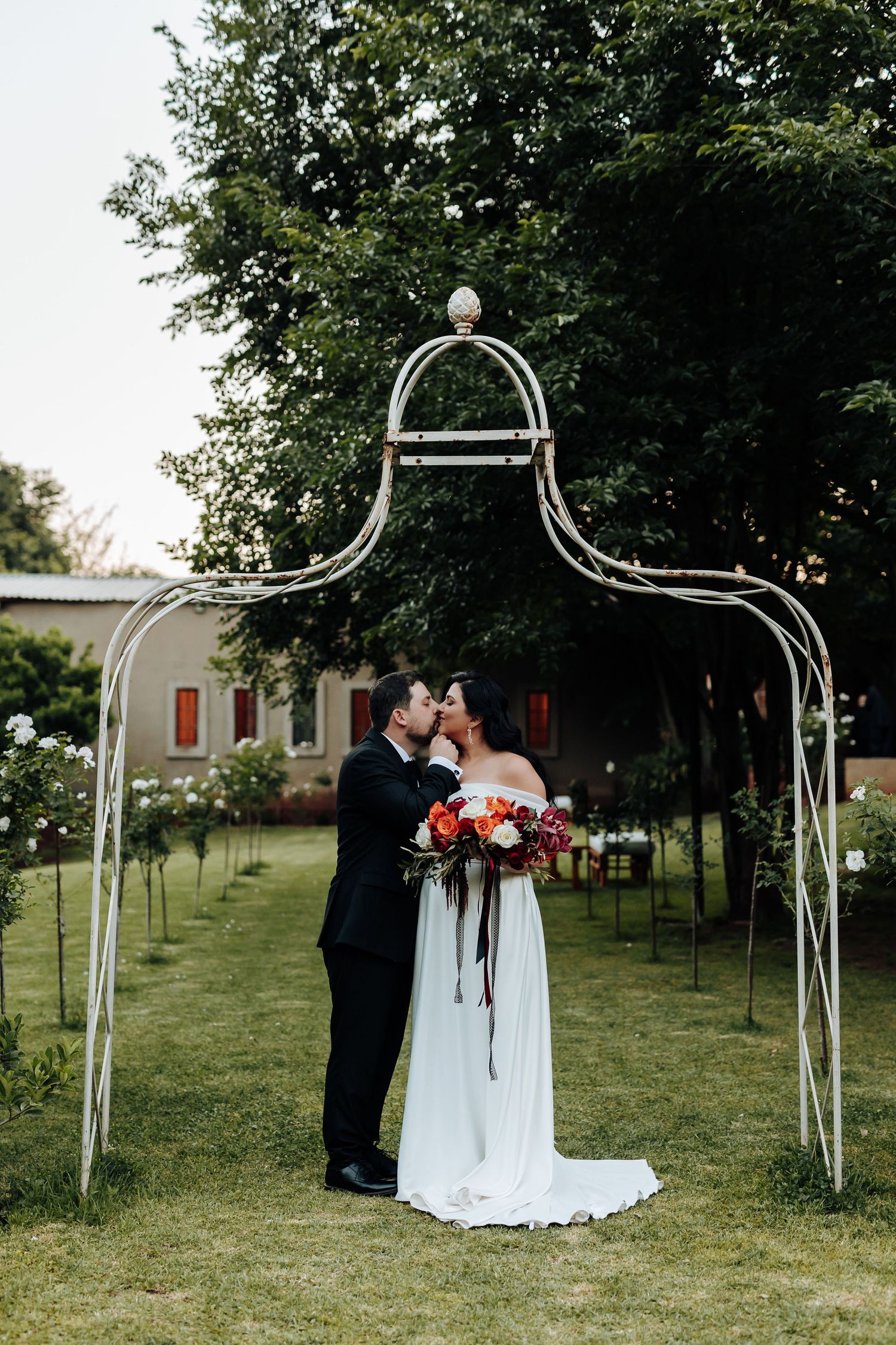 Wedding ceremony setup outdoors with white metal arches lining a grassy aisle.