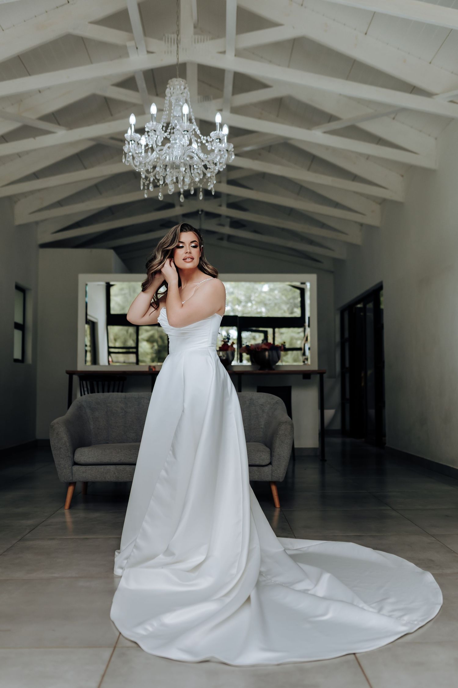 A series of photos showing a flowing white wedding dress with a long train in an elegant room with chandeliers.