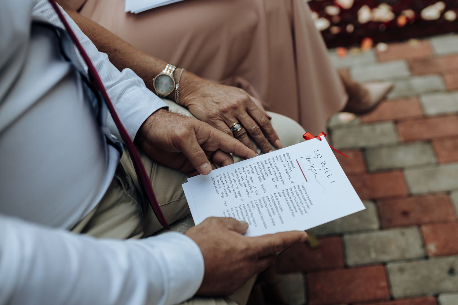 An officiant reviews ceremony notes while holding papers outdoors.