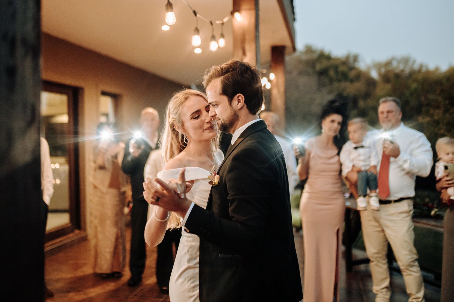 Couple shares an intimate moment during their wedding dance on an outdoor patio.