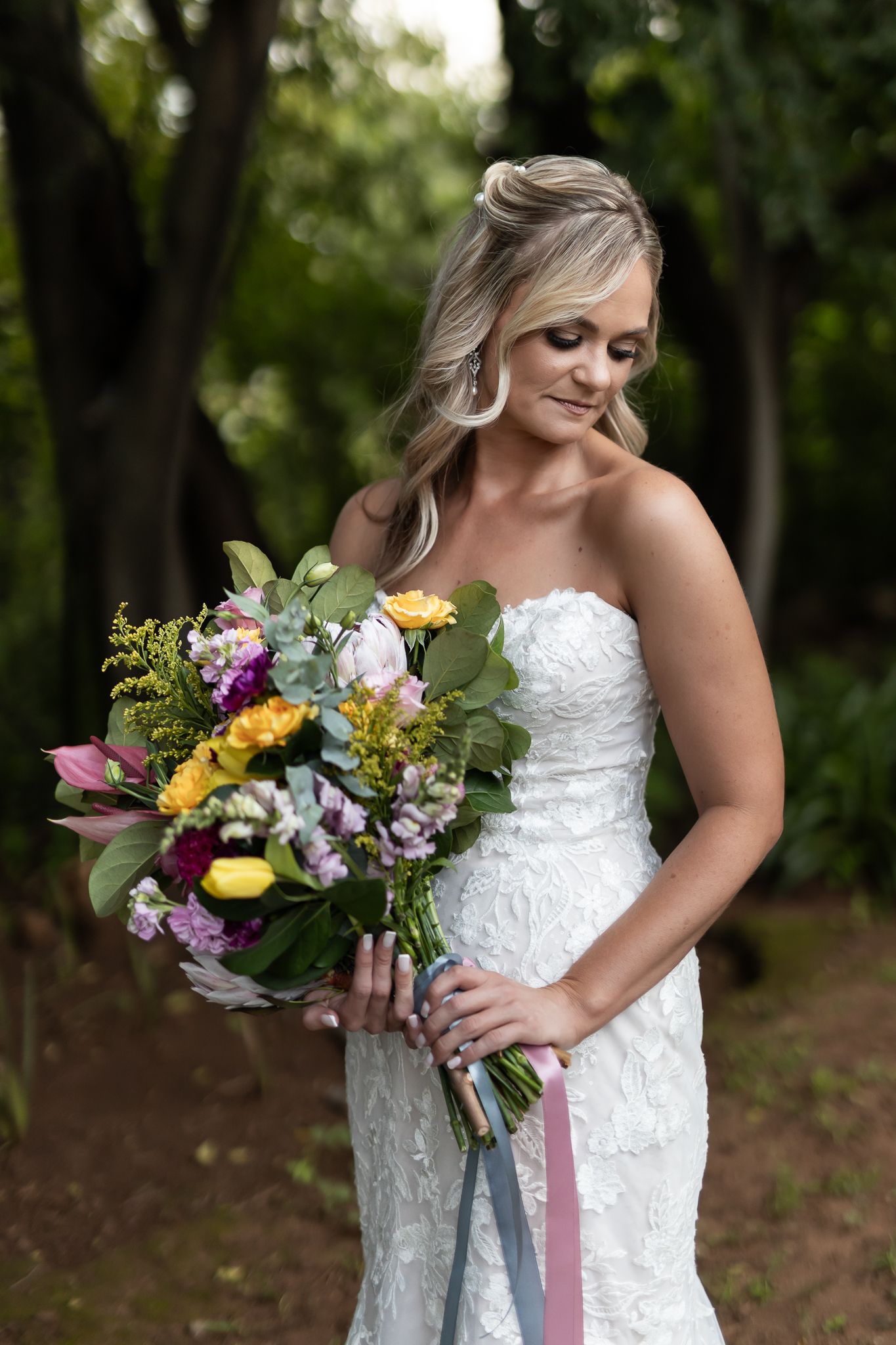 A wedding dress portrait in a garden setting with a vibrant mixed floral bouquet.