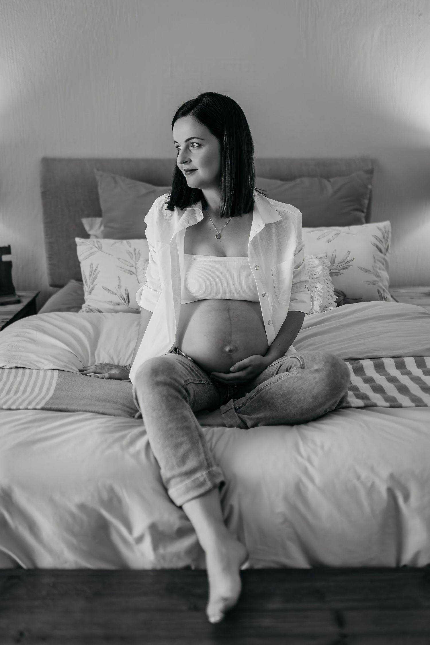 Black and white photo series of person lounging on white bedding in casual attire.