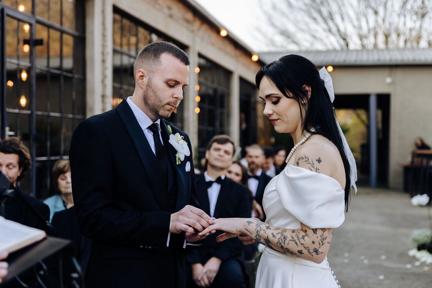 Couple dances together at their wedding reception while guests watch in formal indoor venue.