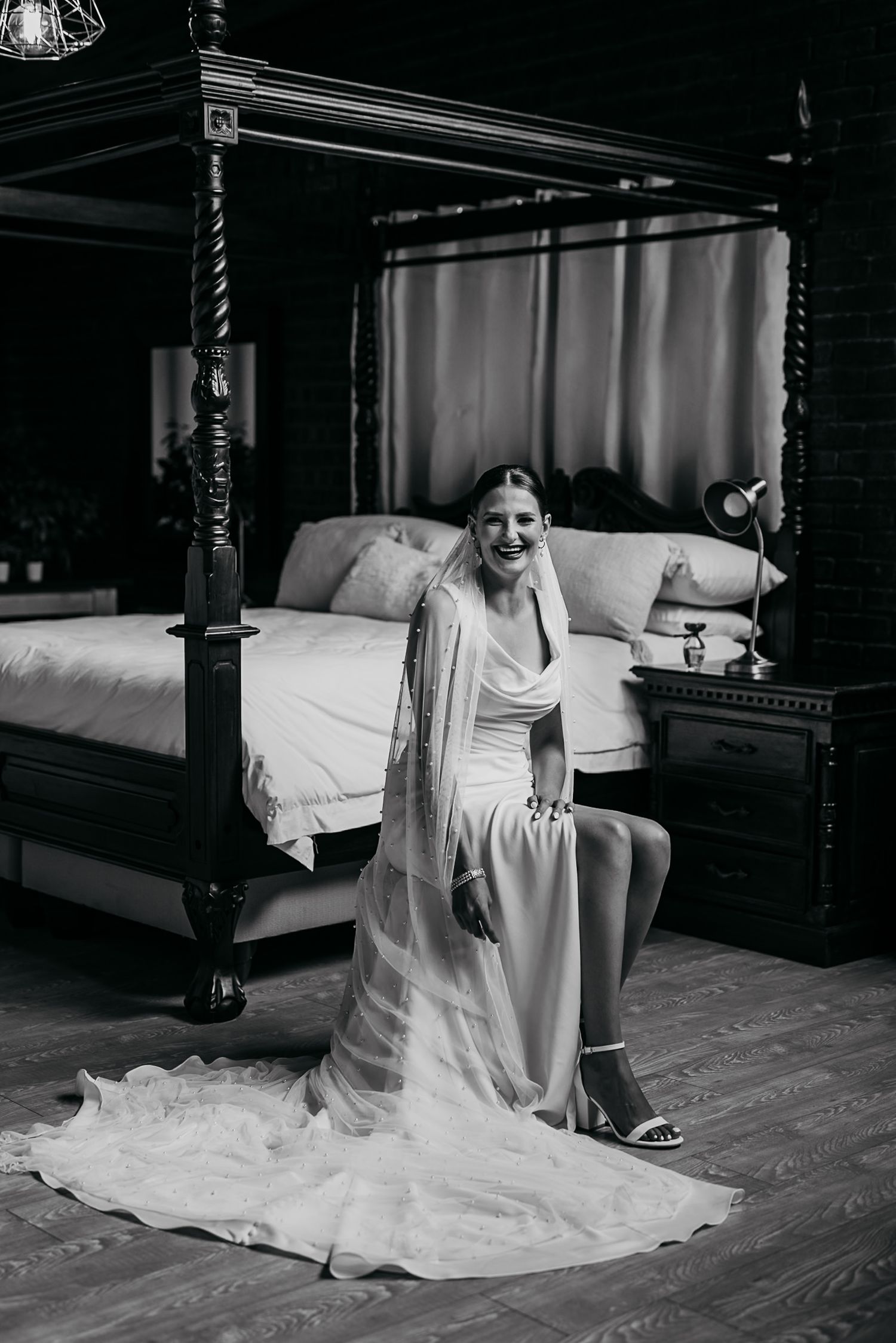 Black and white wedding photography capturing intimate moments in an elegant bedroom setting.