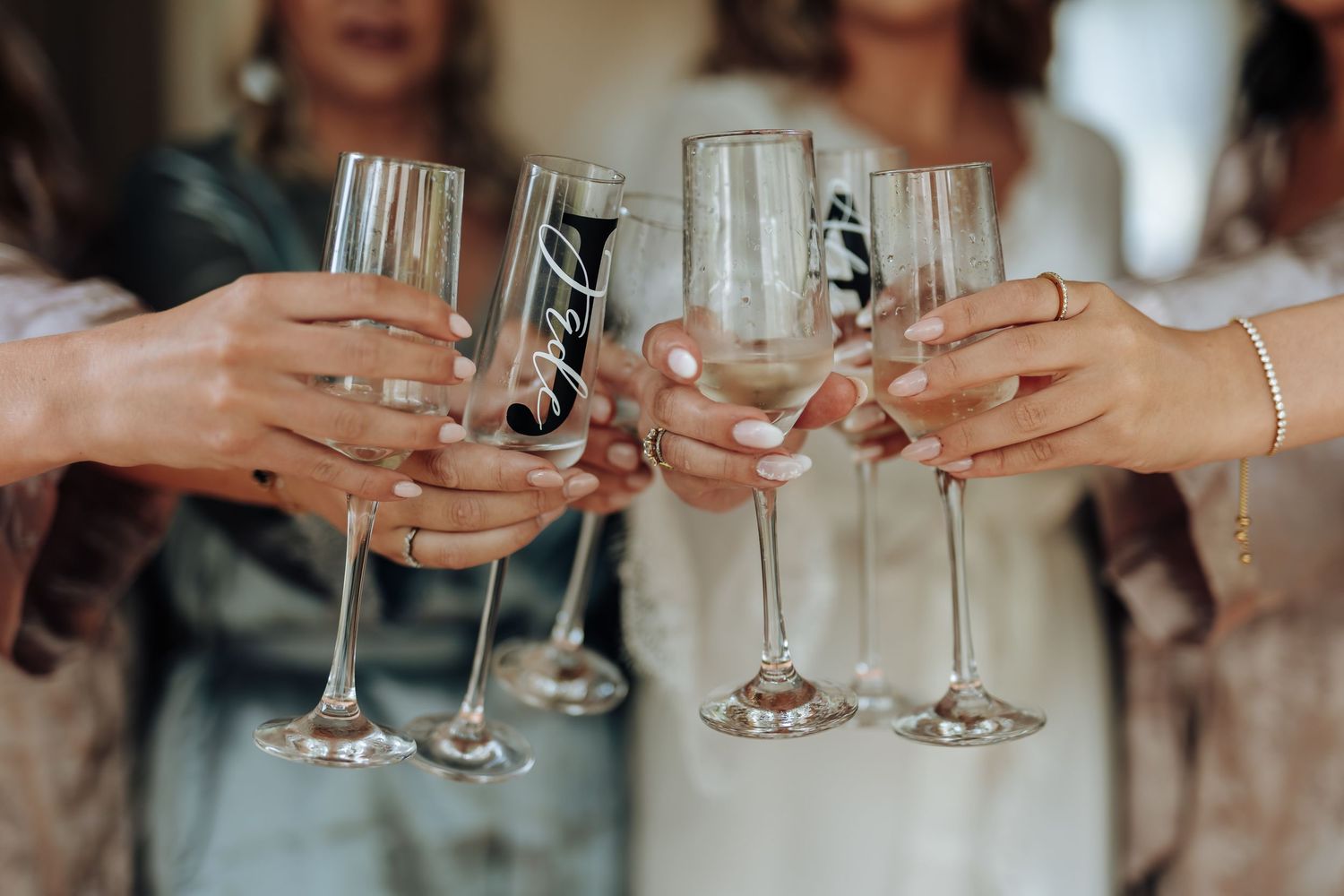 Several hands raise champagne glasses in a celebratory toast at a festive gathering.