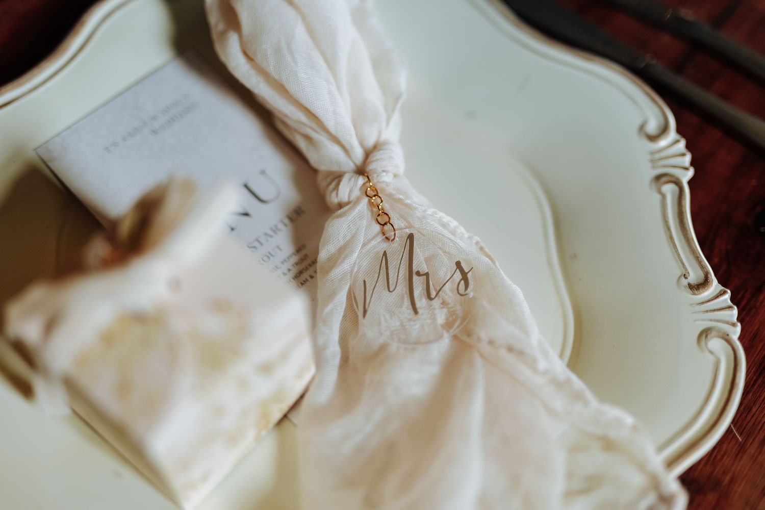 A white monogrammed napkin elegantly folded on an ornate vintage plate.