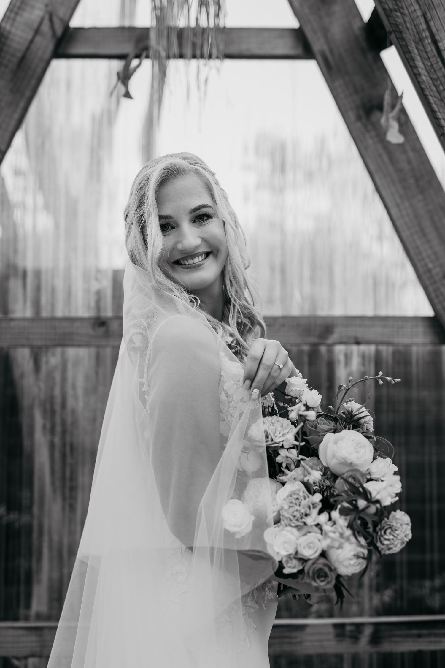 Black and white wedding portraits showing a bride in a veil holding a white floral bouquet in multiple poses.