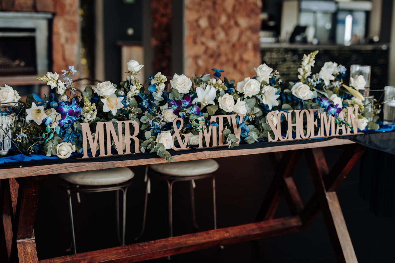 Wedding table decoration with 'Mr & Mrs' sign surrounded by blue and white flowers.