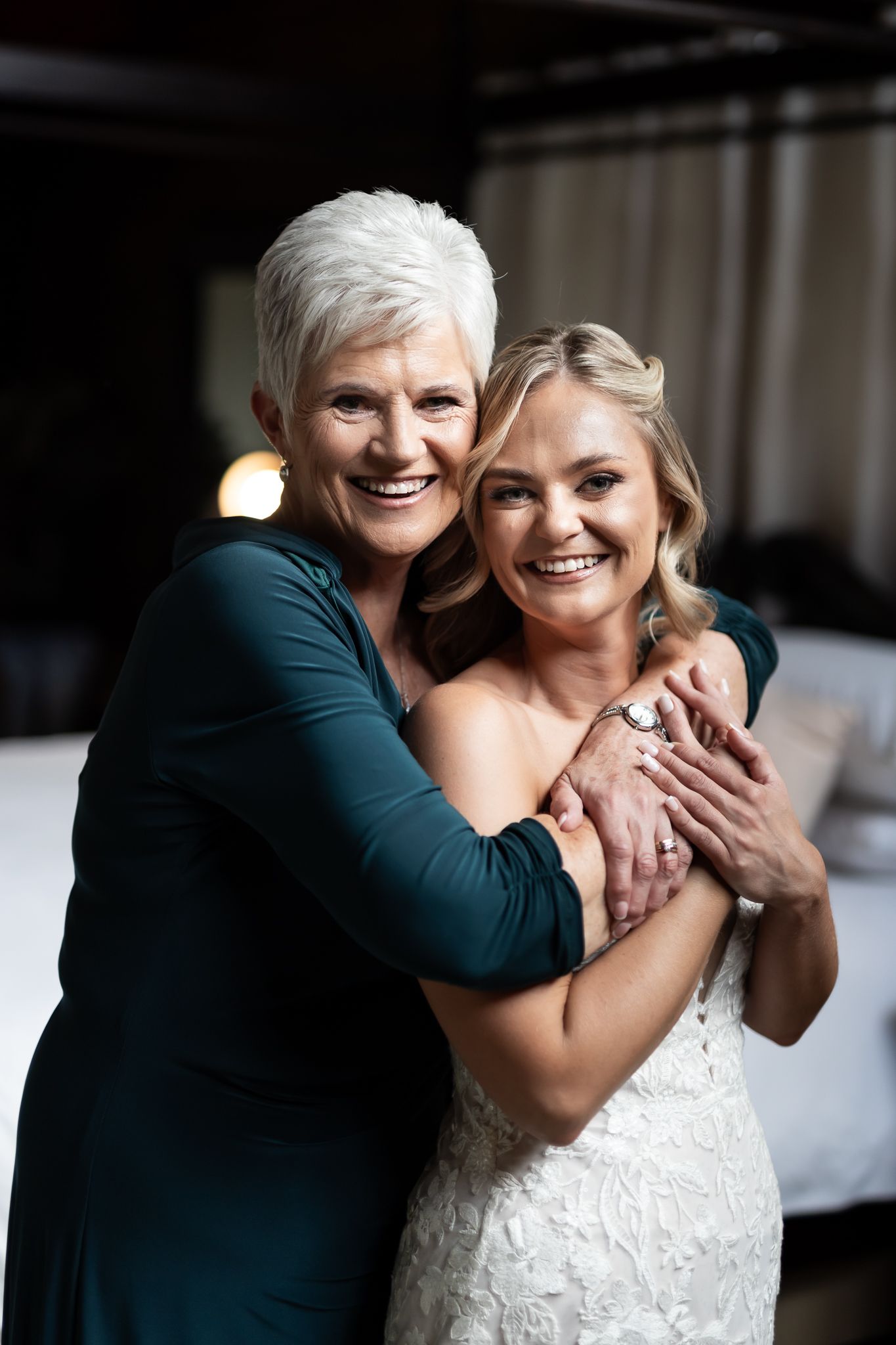 Two women share a heartfelt embrace while getting ready for a wedding celebration.