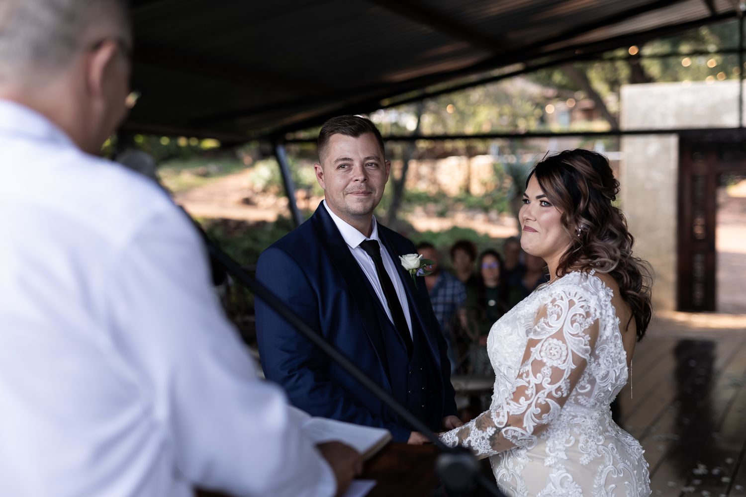 Wedding ceremony under pavilion with officiant leading the service.