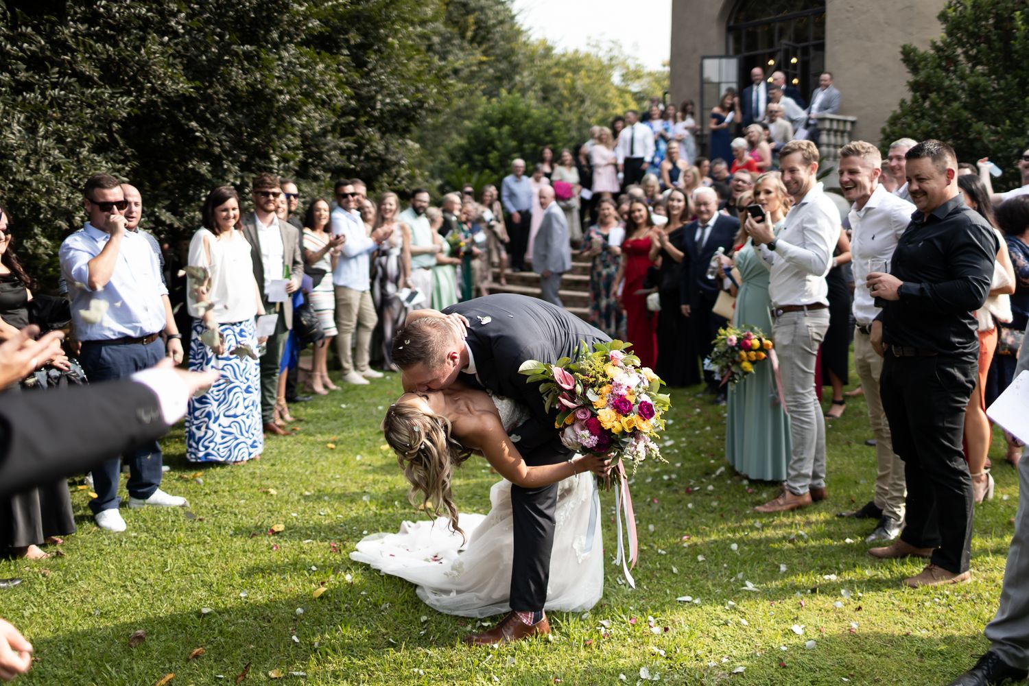 Wedding celebration on church grounds with guests gathered around the couple.