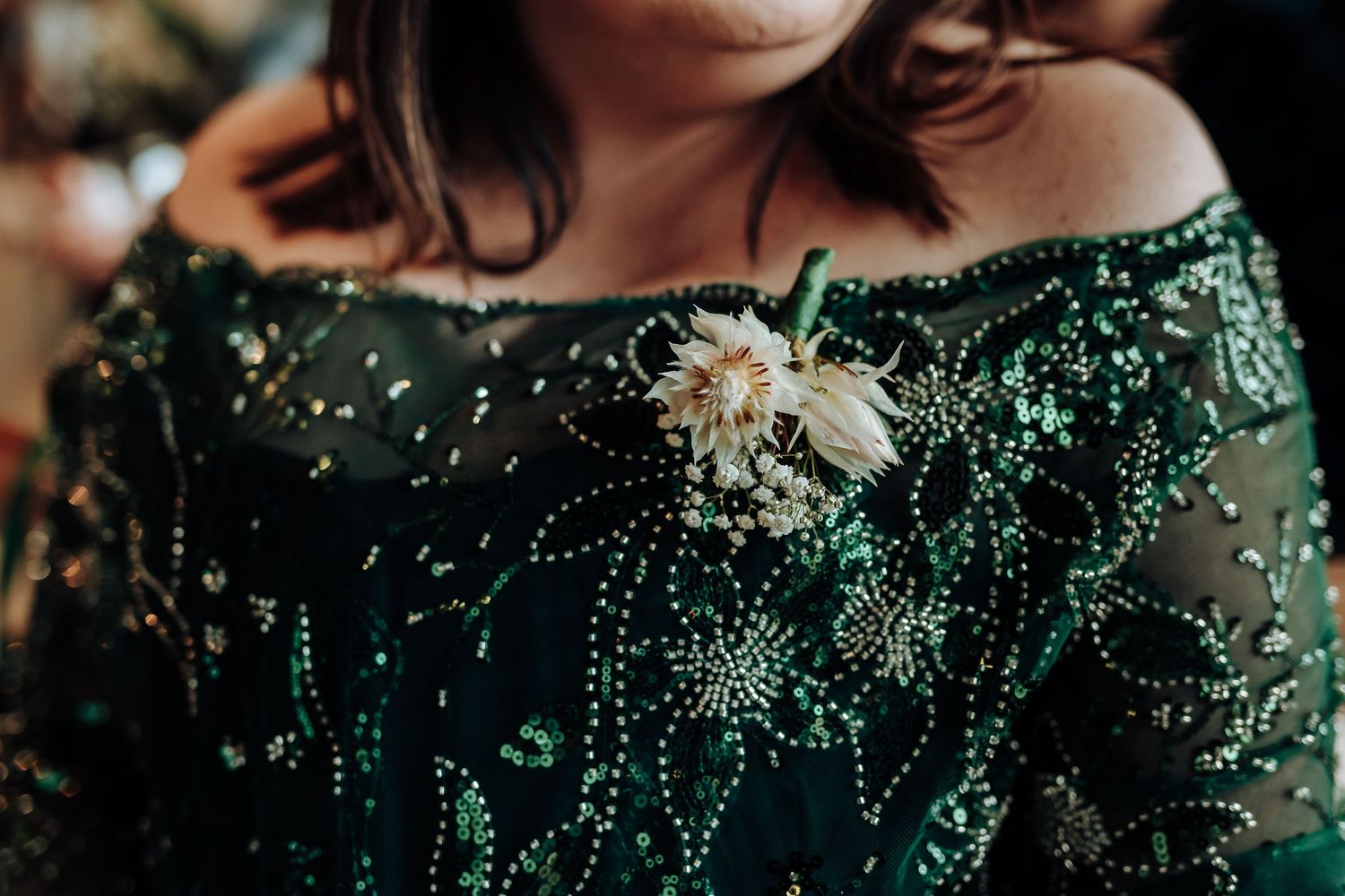Close-up detail of emerald green sequined bridesmaid dress with floral boutonniere.