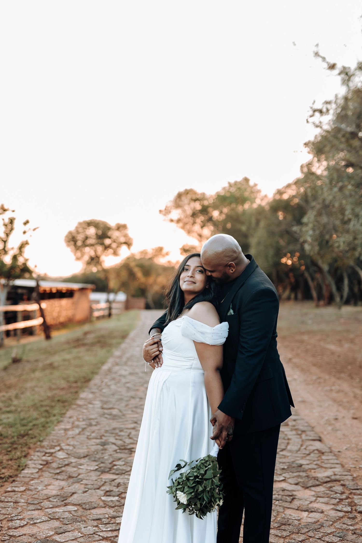 A couple shares an intimate moment on a rustic path during golden hour at their wedding.
