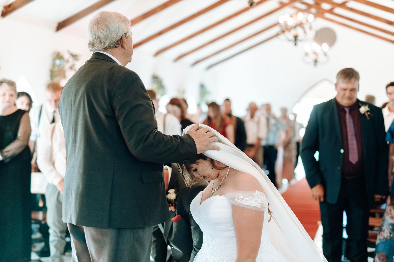 Traditional wedding ceremony with officiant presiding over couple in bright chapel setting.