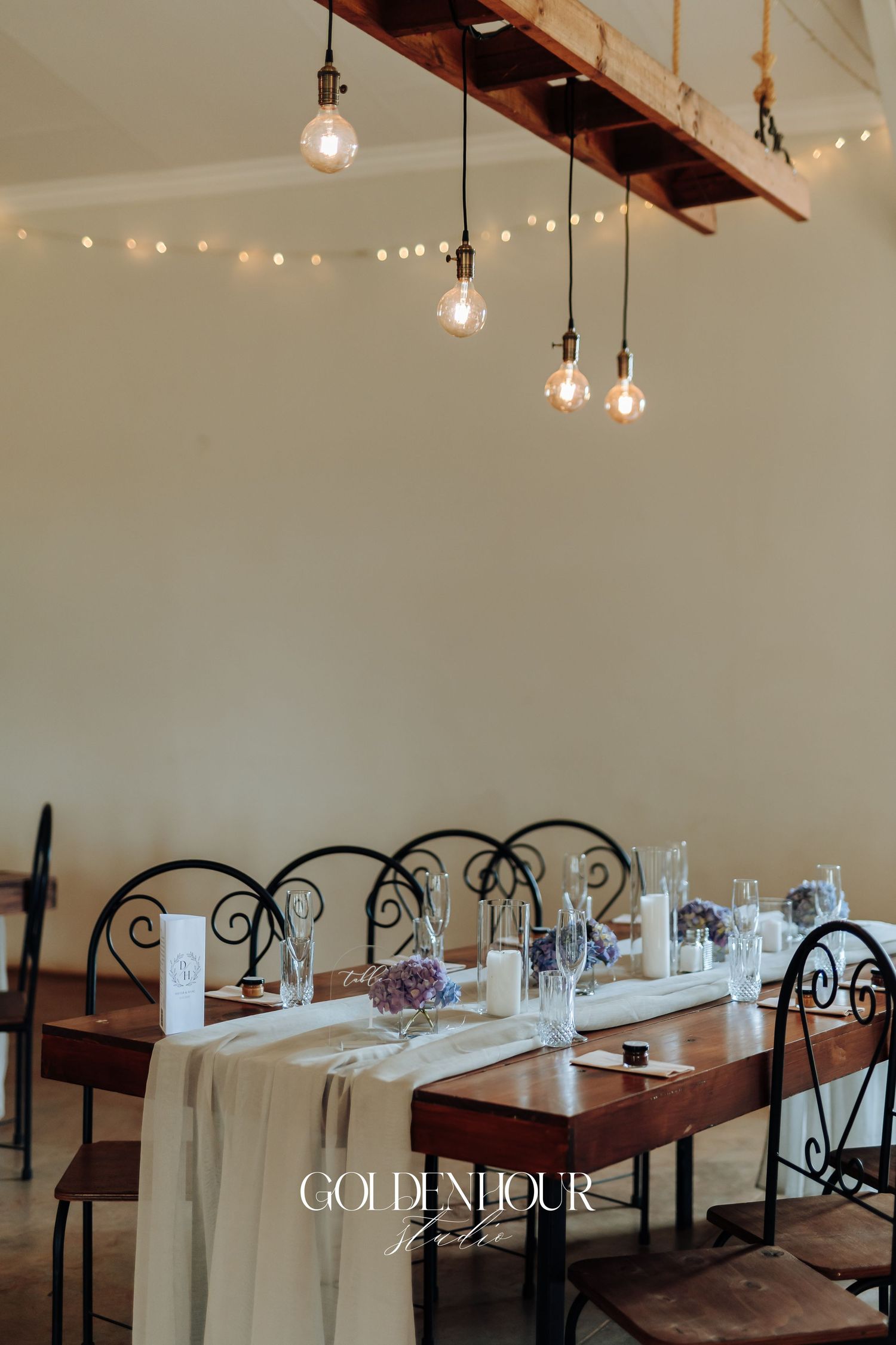 Elegant indoor wedding reception venue with white tablecloths and hanging pendant lights creating a romantic atmosphere.