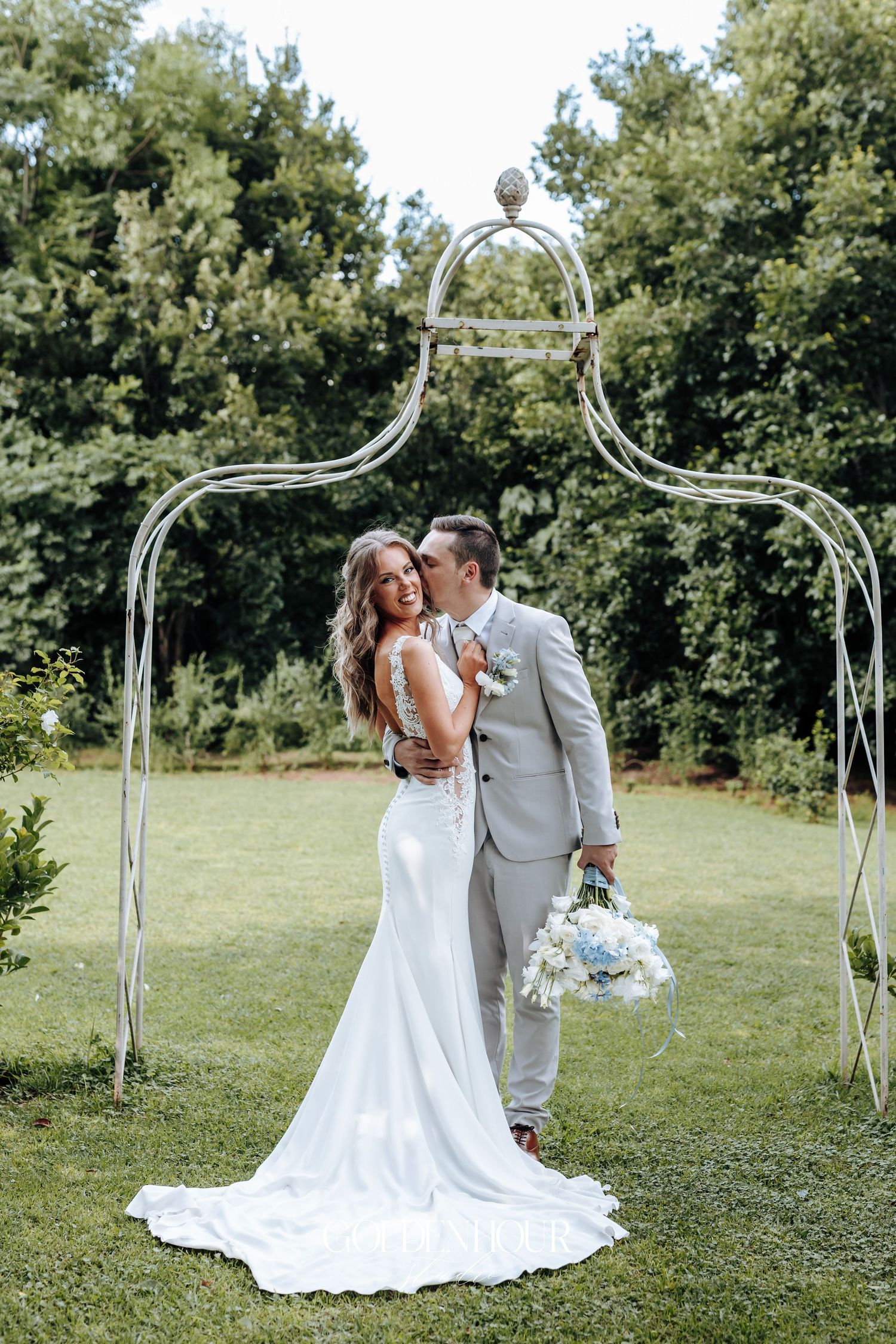 Wedding ceremony setup with elegant white arch in outdoor garden setting.