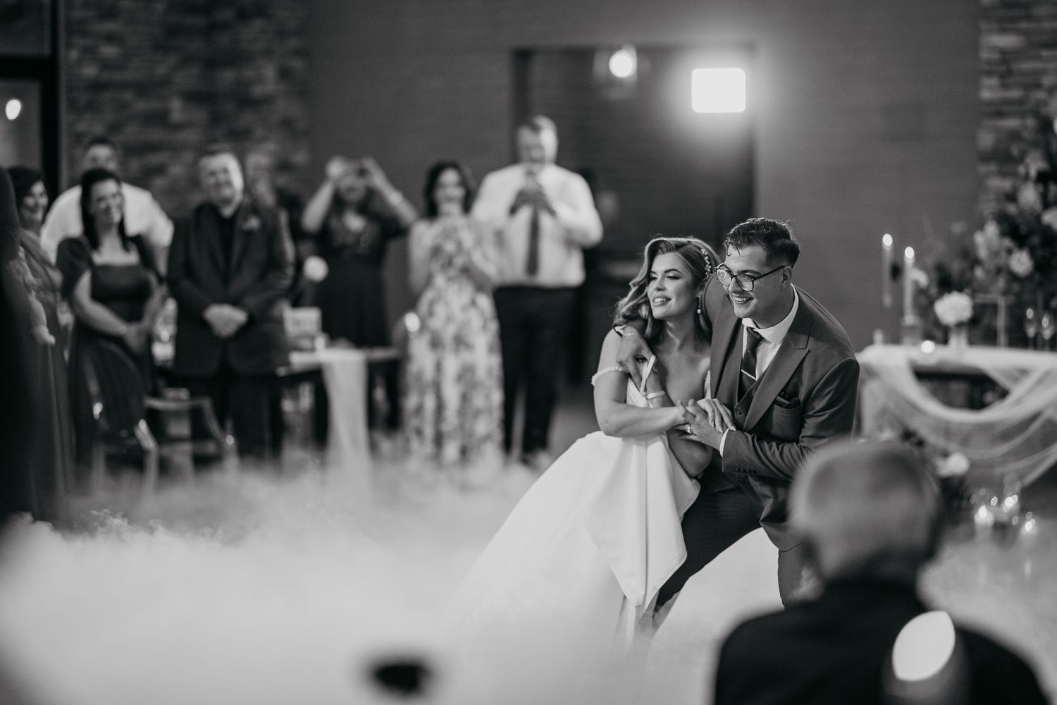 Black and white photo of wedding guests dancing and celebrating at a reception.