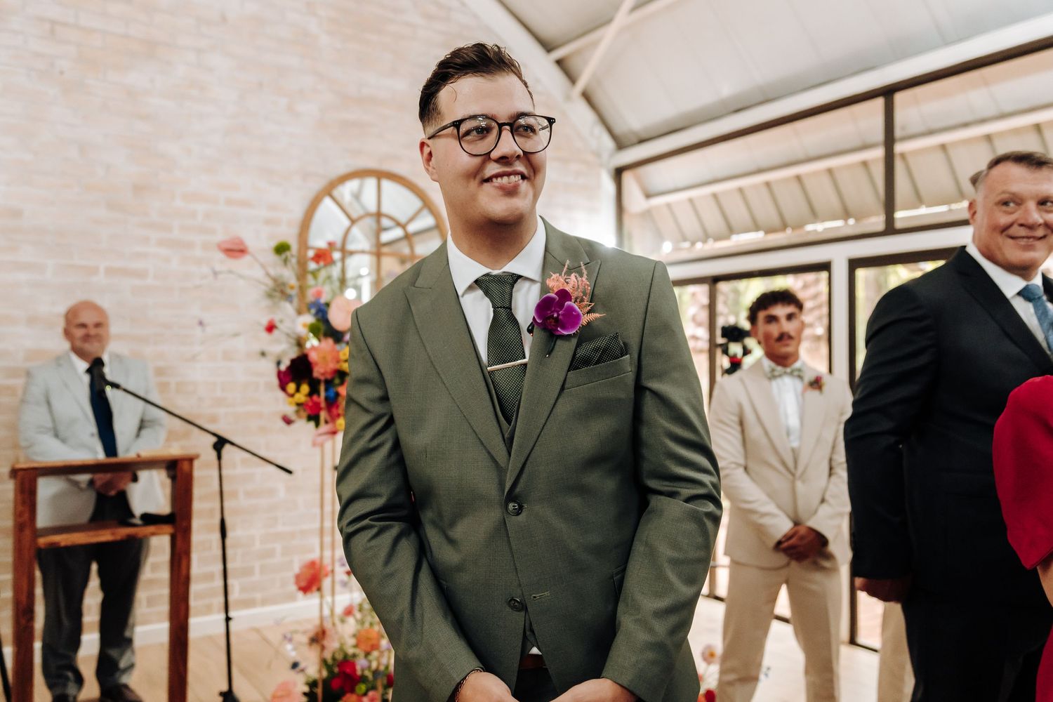 Wedding guests celebrate with confetti during an indoor ceremony at a bright, airy venue.