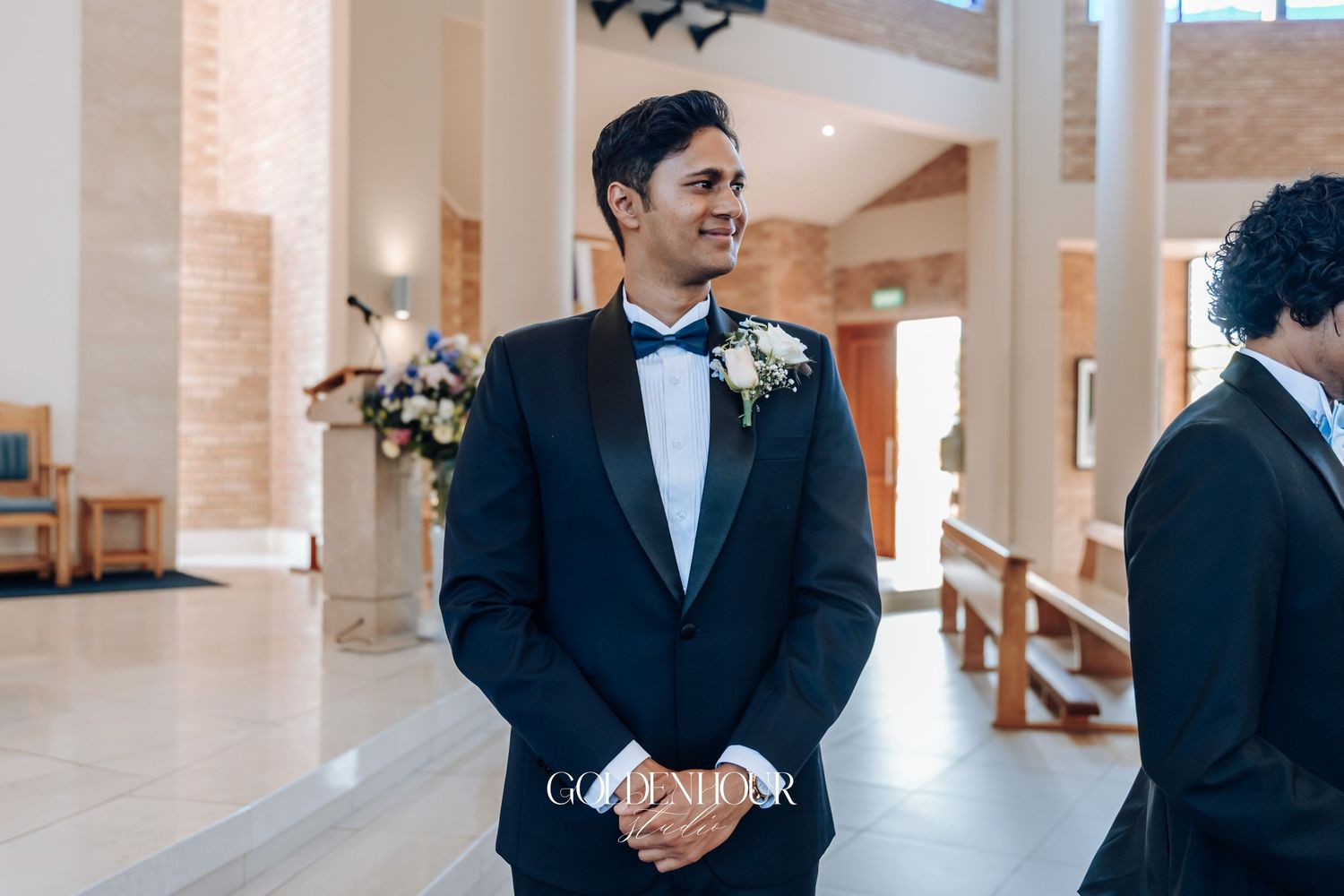 Wedding party members in black tuxedos stand in elegant church hallway.